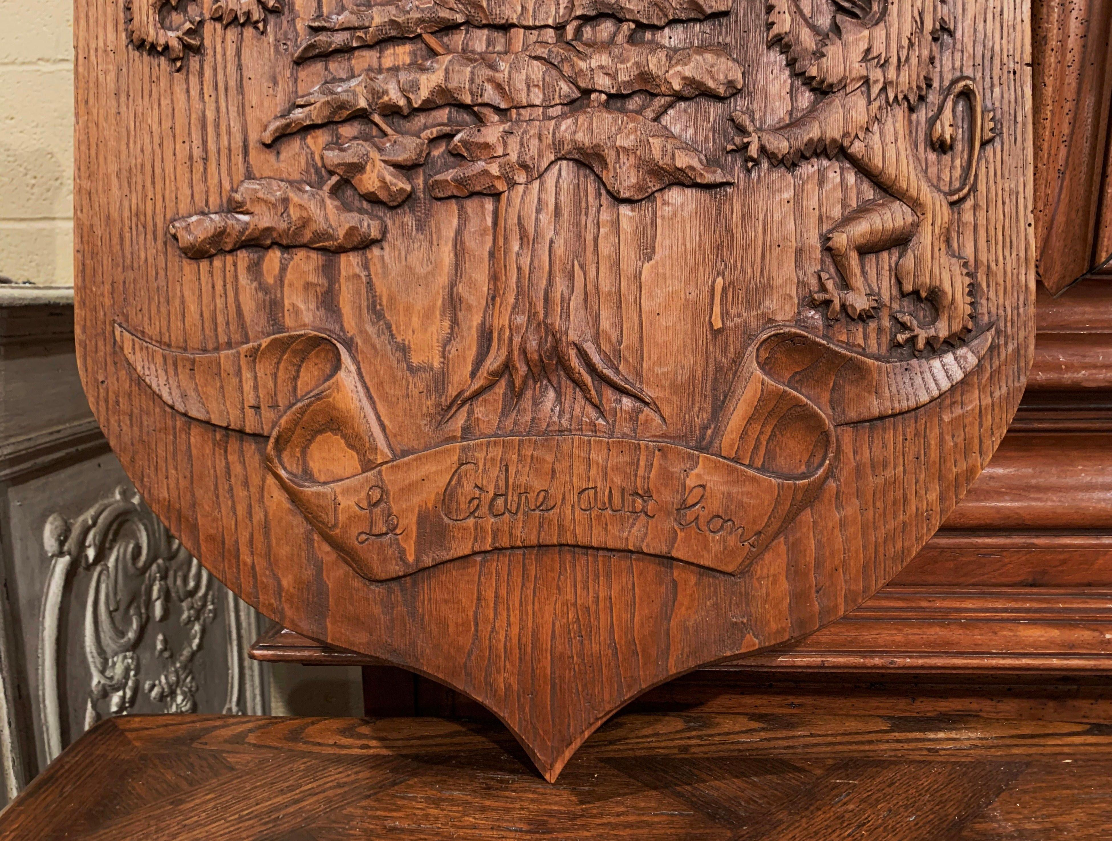 Decorate a wall in a study or den with this elegant, antique coat of arms sculpture. Crafted in France, circa 1920, the large Gothic style shield is heavily carved with a cedar tree flanked by lion sculptures; the decorative shield is further