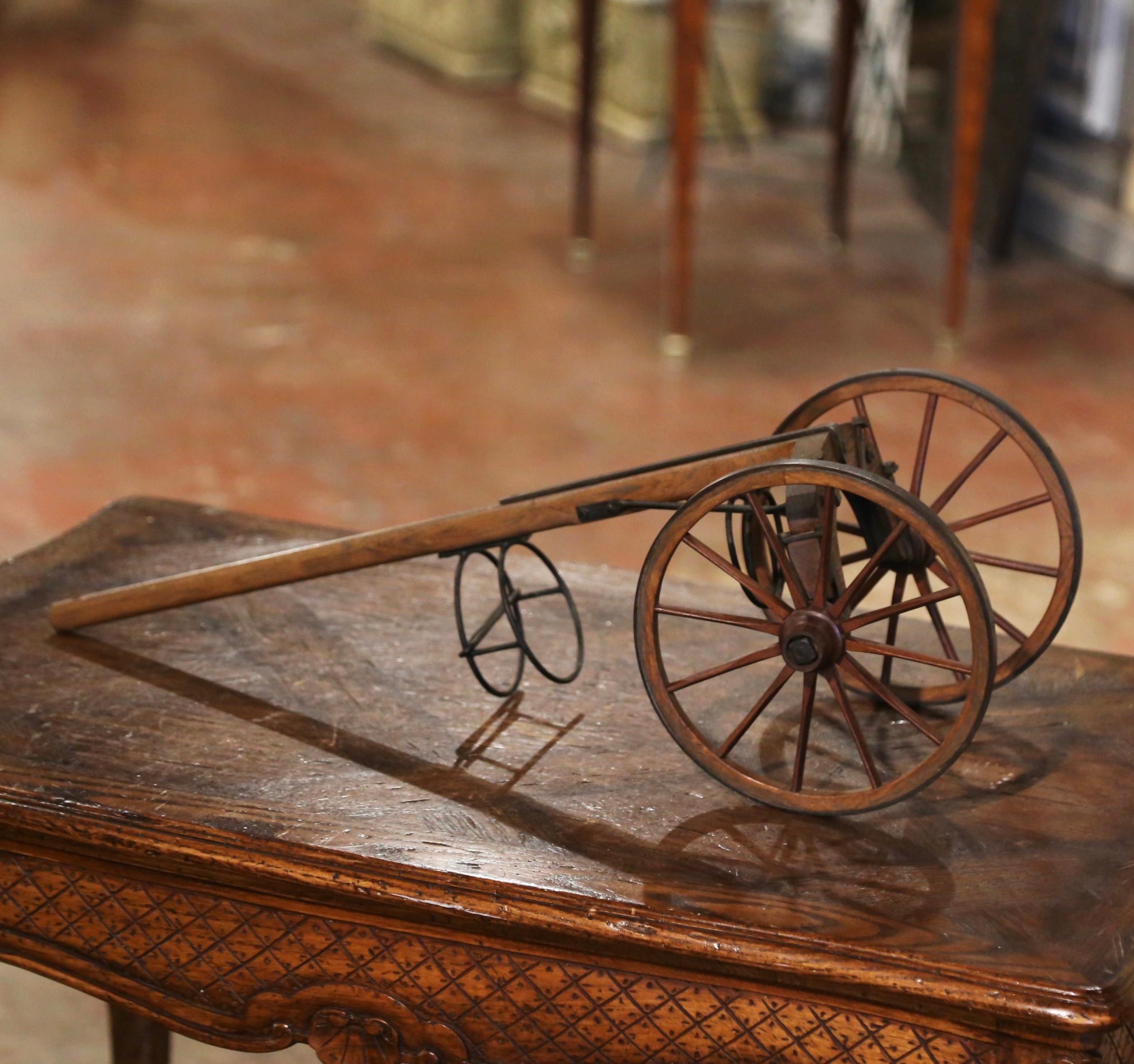 Decorate a dining table or a wine cellar with this elegant antique wine bottle display. Crafted in France circa 1920, the trolley made of oak wood and iron features a wine bottle holder set over two wheels with a pulling wooden handle. The cart is