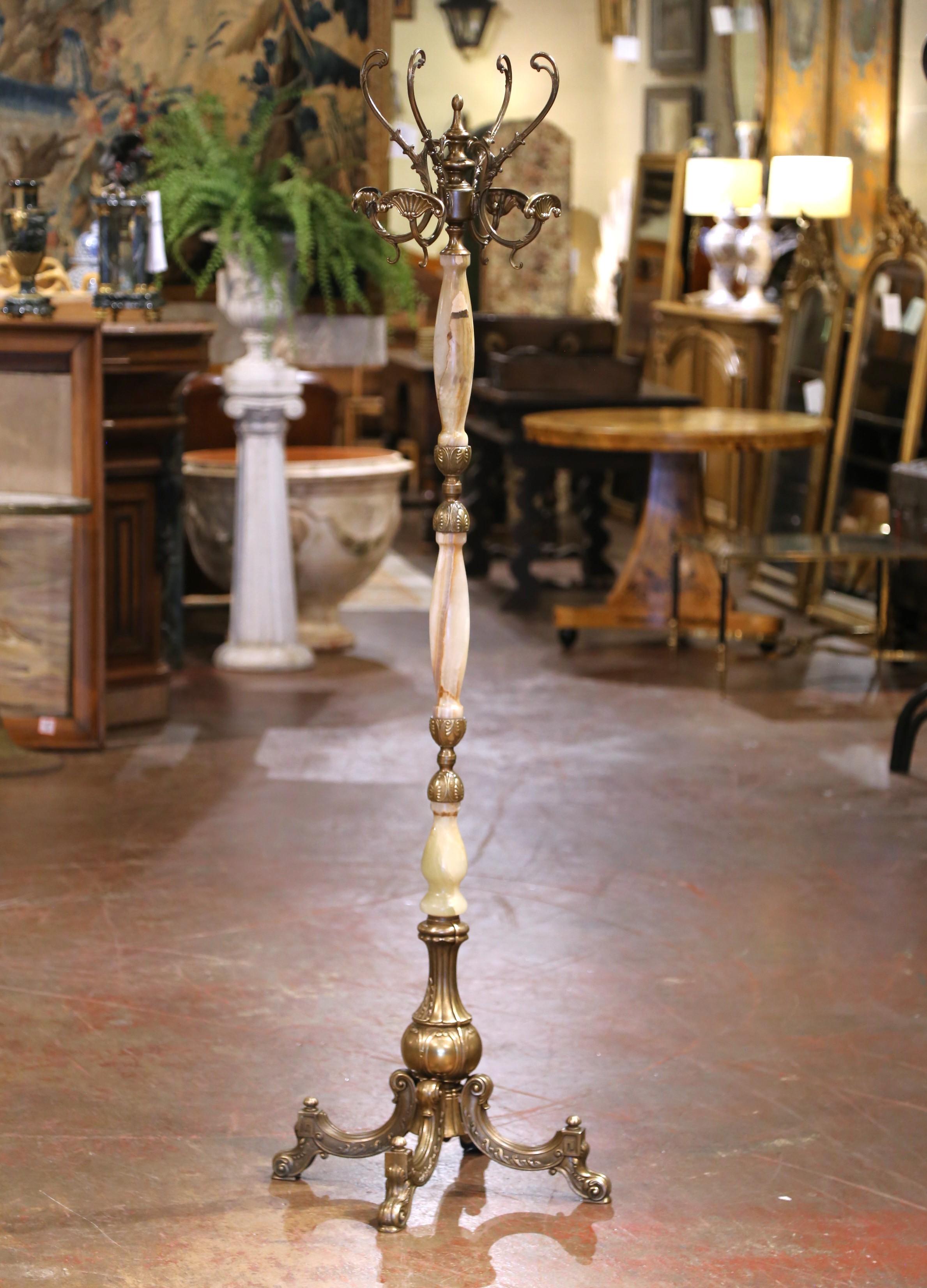 Questo antico albero da ingresso in onice e ottone intagliato è stato realizzato in Francia, intorno al 1920. Poggiata su un'intricata base vasiforme che termina con piedi quadripartiti con motivi a forma di delfino e foglie d'acanto, l'alta