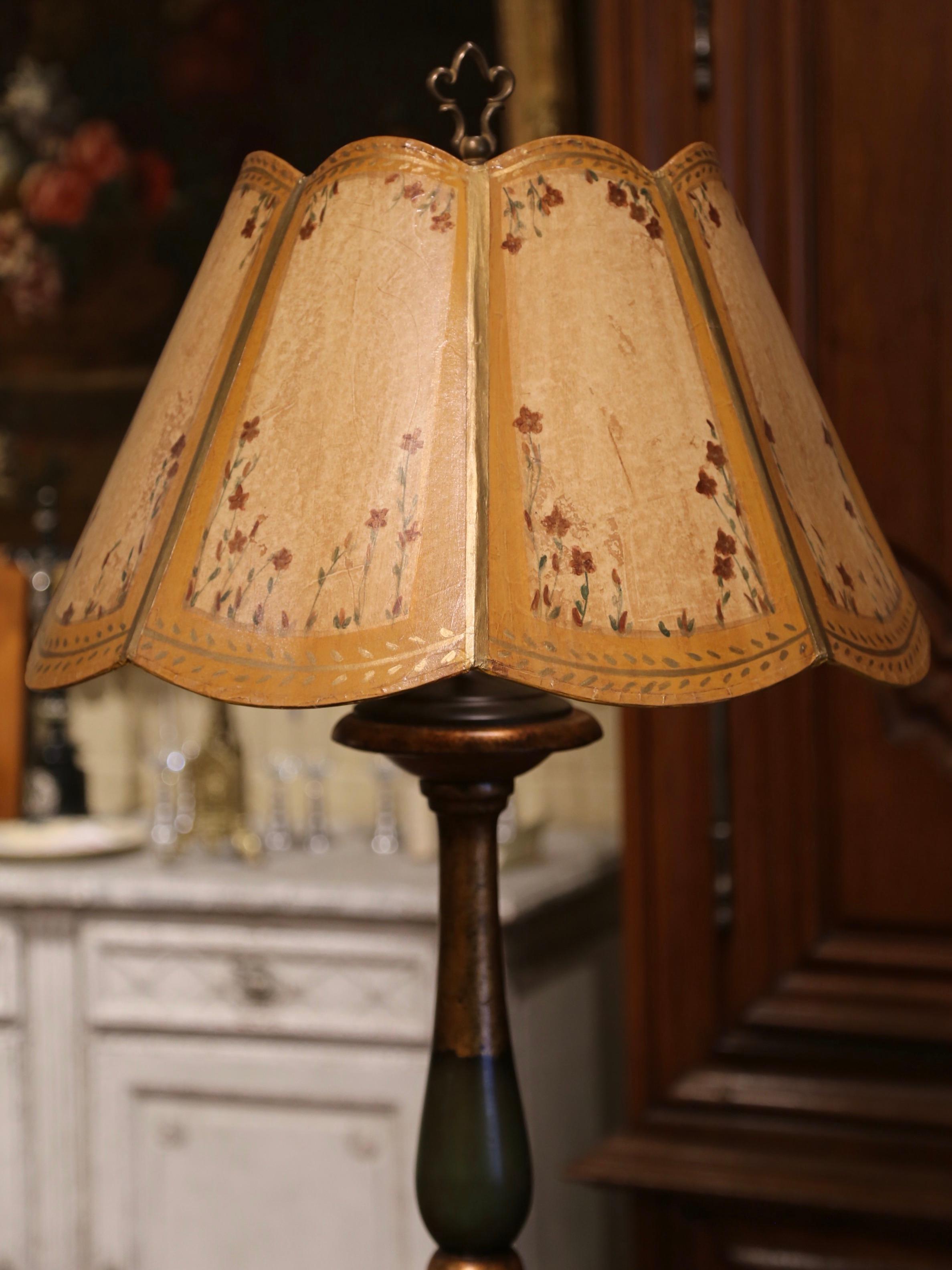 This elegant antique floor lamp was crafted in France, circa 1920. The lamp stands on a round stem over a long carved and turned stem. The fixture is dressed with a single center light and embellished with a custom shade decorated with hand painted