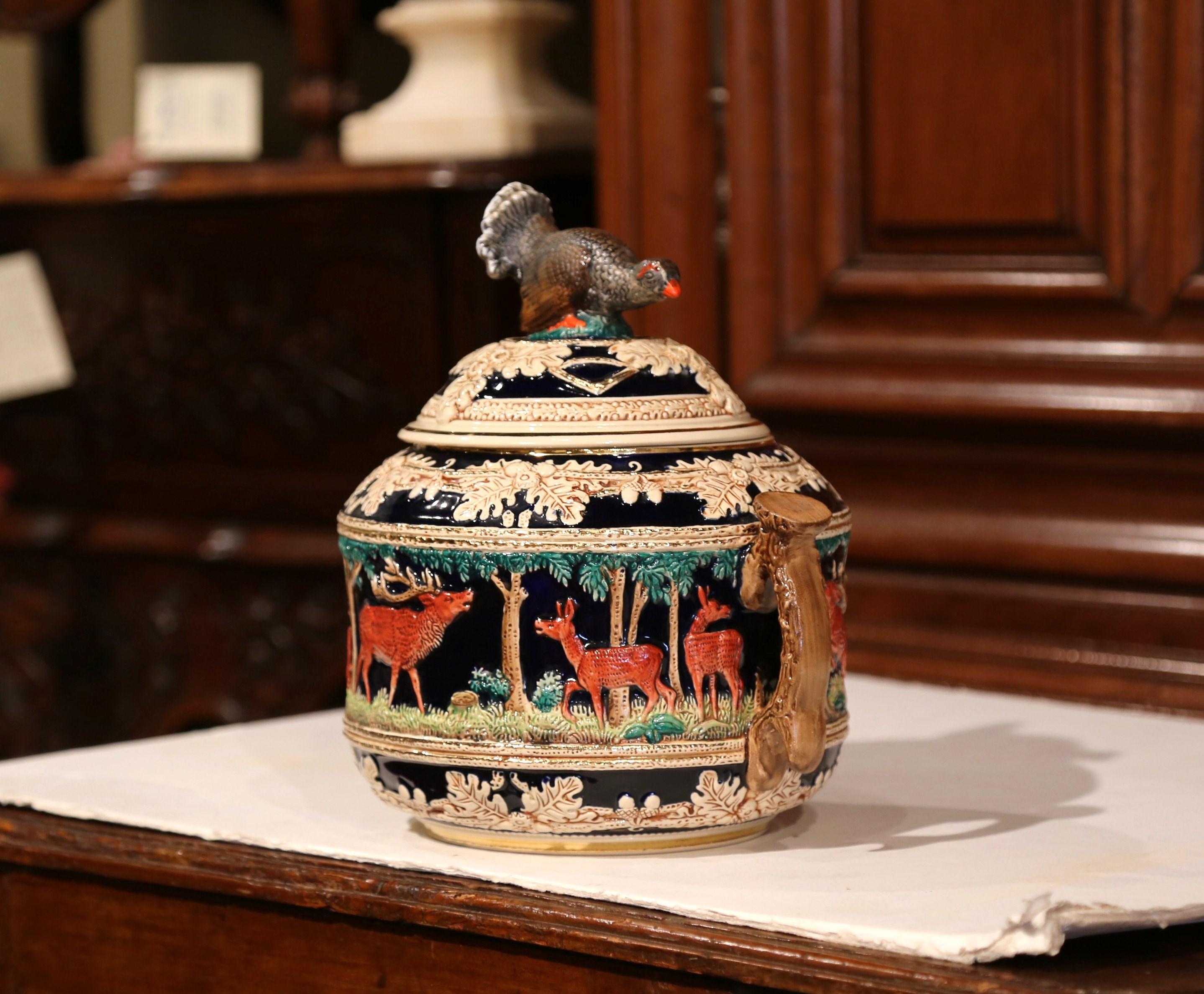 Embellish your dining room table with this elegant and colorful centre piece. Crafted in northern France, circa 1920, the dish with antler shaped handles, has hunting decor including deer figures all around carved turkey sculpture on the top lid.