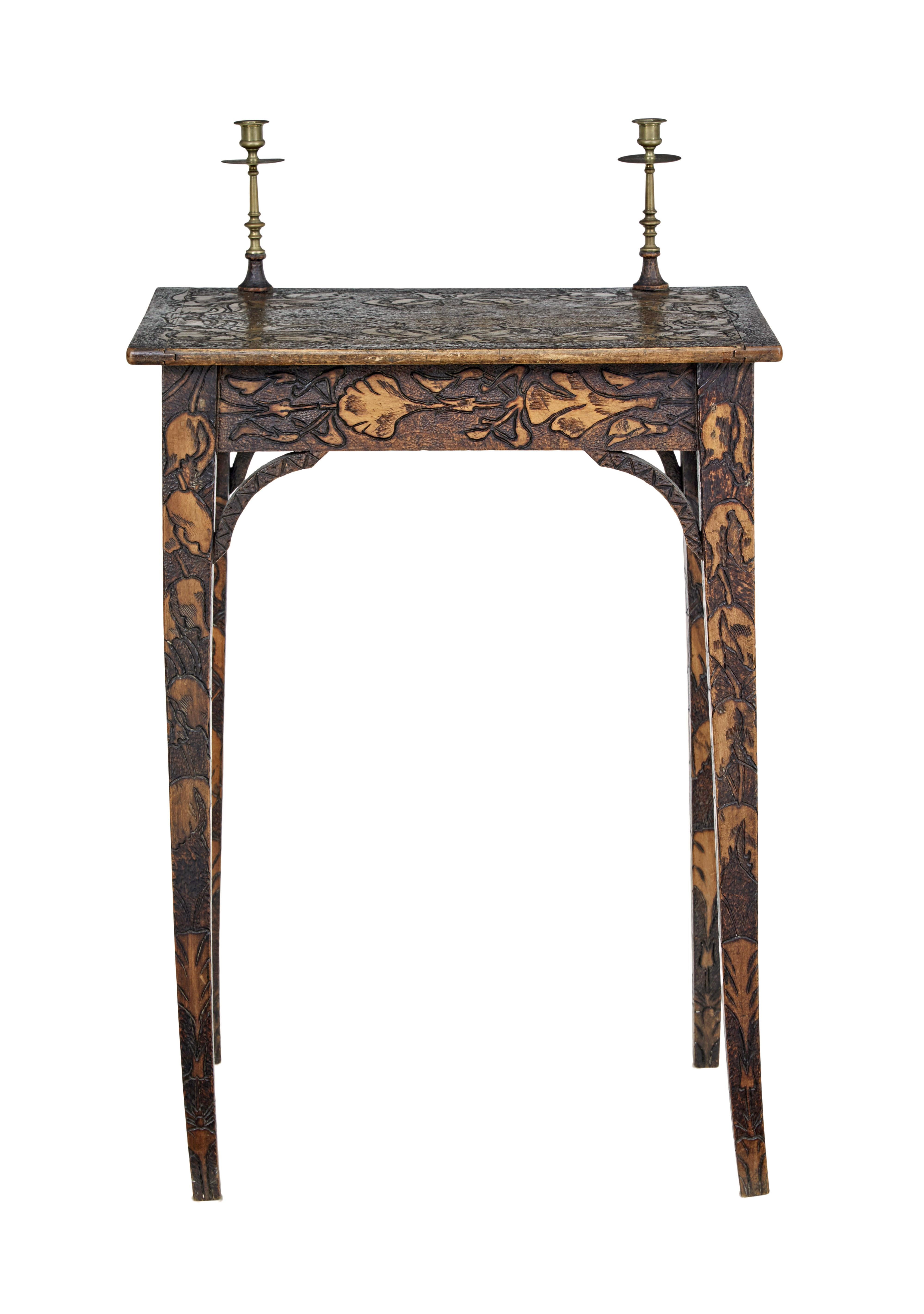 Early 20th century french carved poker work writing table circa 1900.

Unusual profusely carved small writing table. Carved tulips into the top surface, around the apron and down the legs. 2 original brass candle sticks fixed on the top surface.