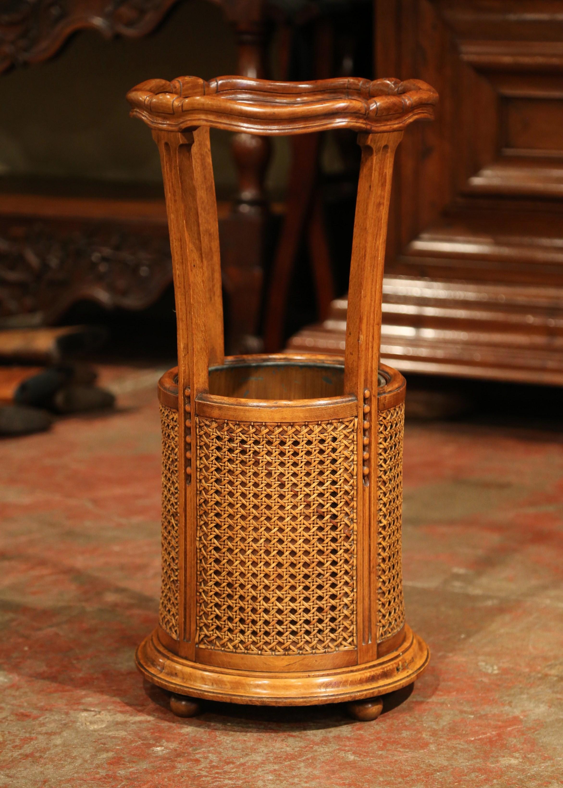 Place this elegant fruit wood stand at your front door or in your mudroom to catch canes and umbrellas. Crafted in France, circa 1900, the circular Parisian basket sits on four round feet and features well-maintained cane decor around the lower