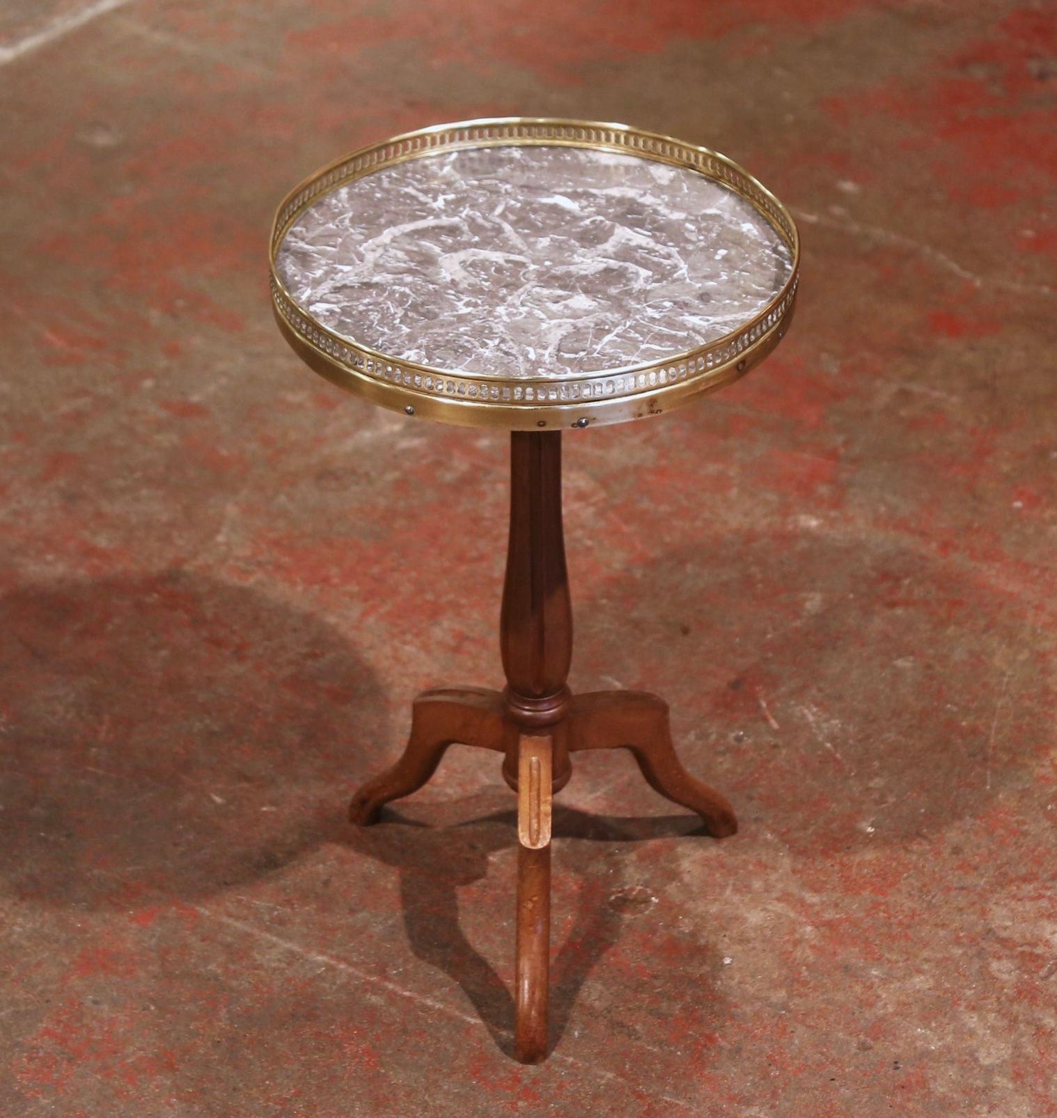 This elegant antique fruitwood and marble table was created in France, circa 1920. The pedestal stands on an intricate turned stem ending with three legs. The top is dressed with a circular variegated grey marble set inside a decorative pierced