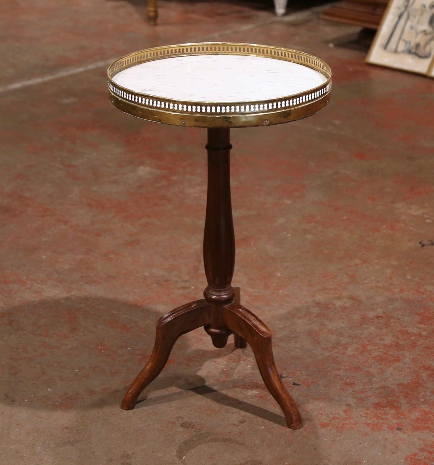 This elegant antique fruitwood and marble table was created in France, circa 1920. The pedestal stands on an intricate tapered stem ending with three scrolled legs. The top is dressed with a circular white marble set inside a decorative pierced