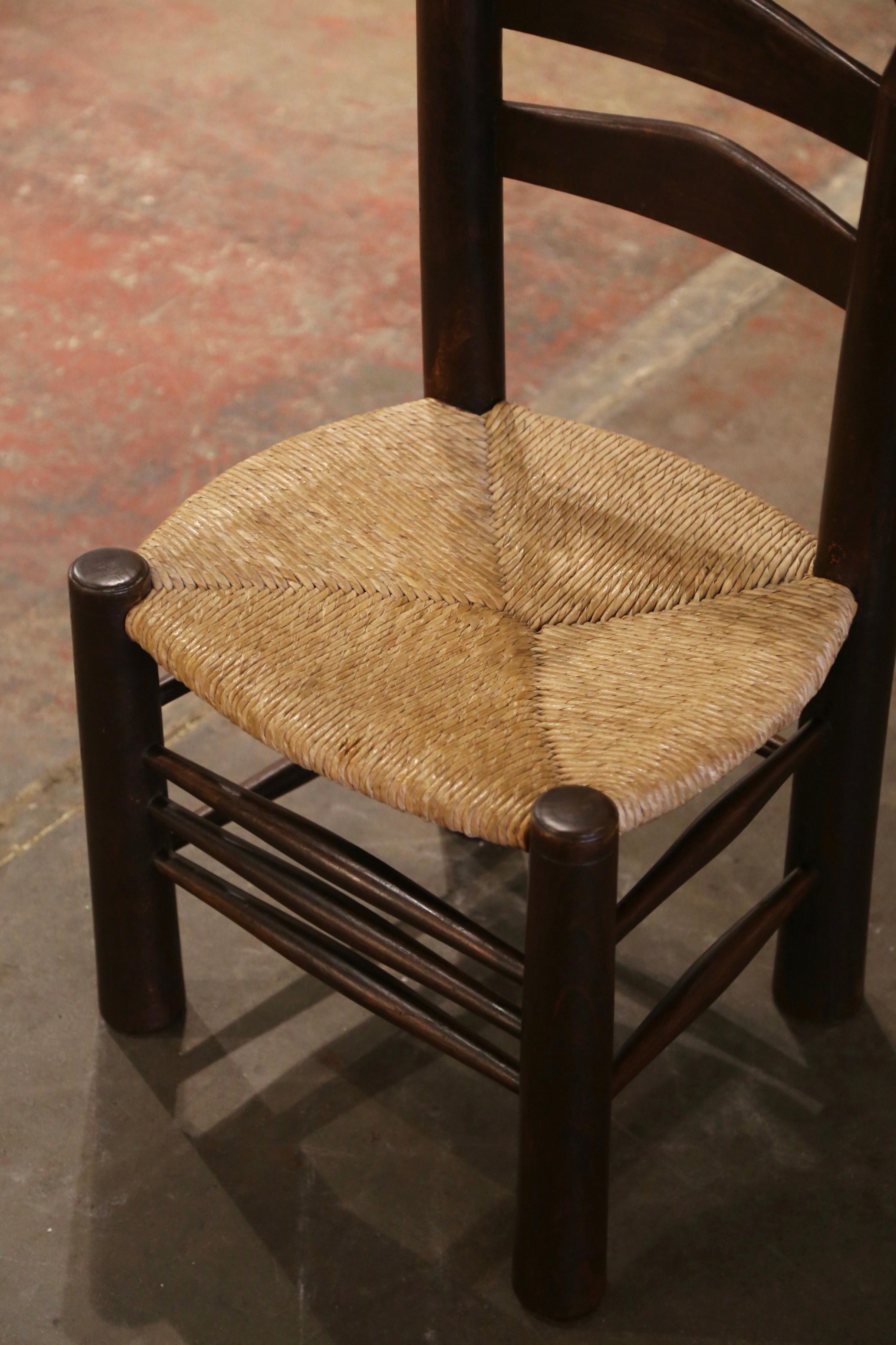 Cette très confortable chaise d'enfant ancienne à dossier en échelle a été fabriquée en Normandie, en France, vers 1940. Construite en bois de noyer et attribuée à Charles Dudouyt, la chaise repose sur des pieds ronds et tournés et présente deux