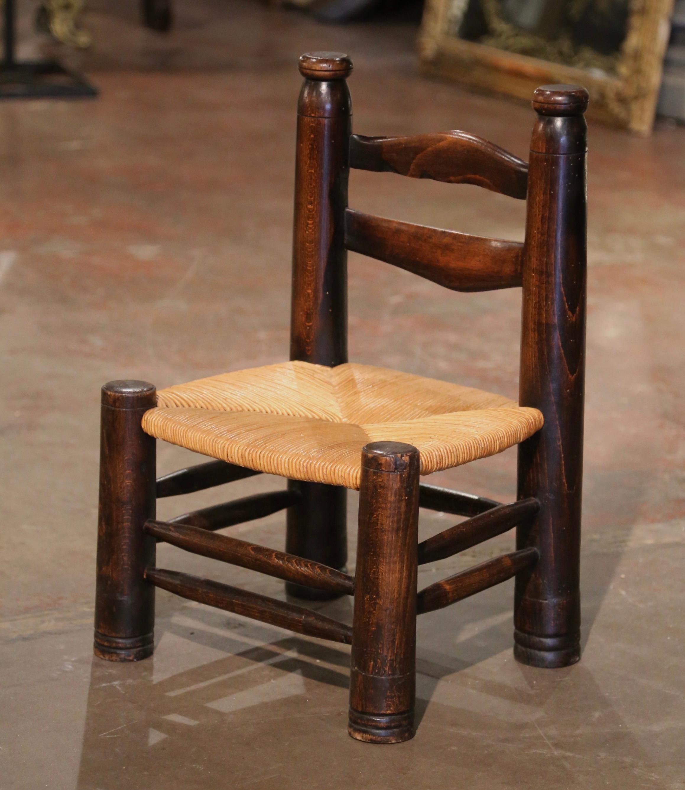 Questa comodissima sedia antica con schienale a scaletta è stata realizzata in Normandia, Francia, intorno al 1940. Costruita in legno di noce e attribuita a Charles Dudouyt, la sedia poggia su gambe rotonde tornite e presenta due scale nella parte
