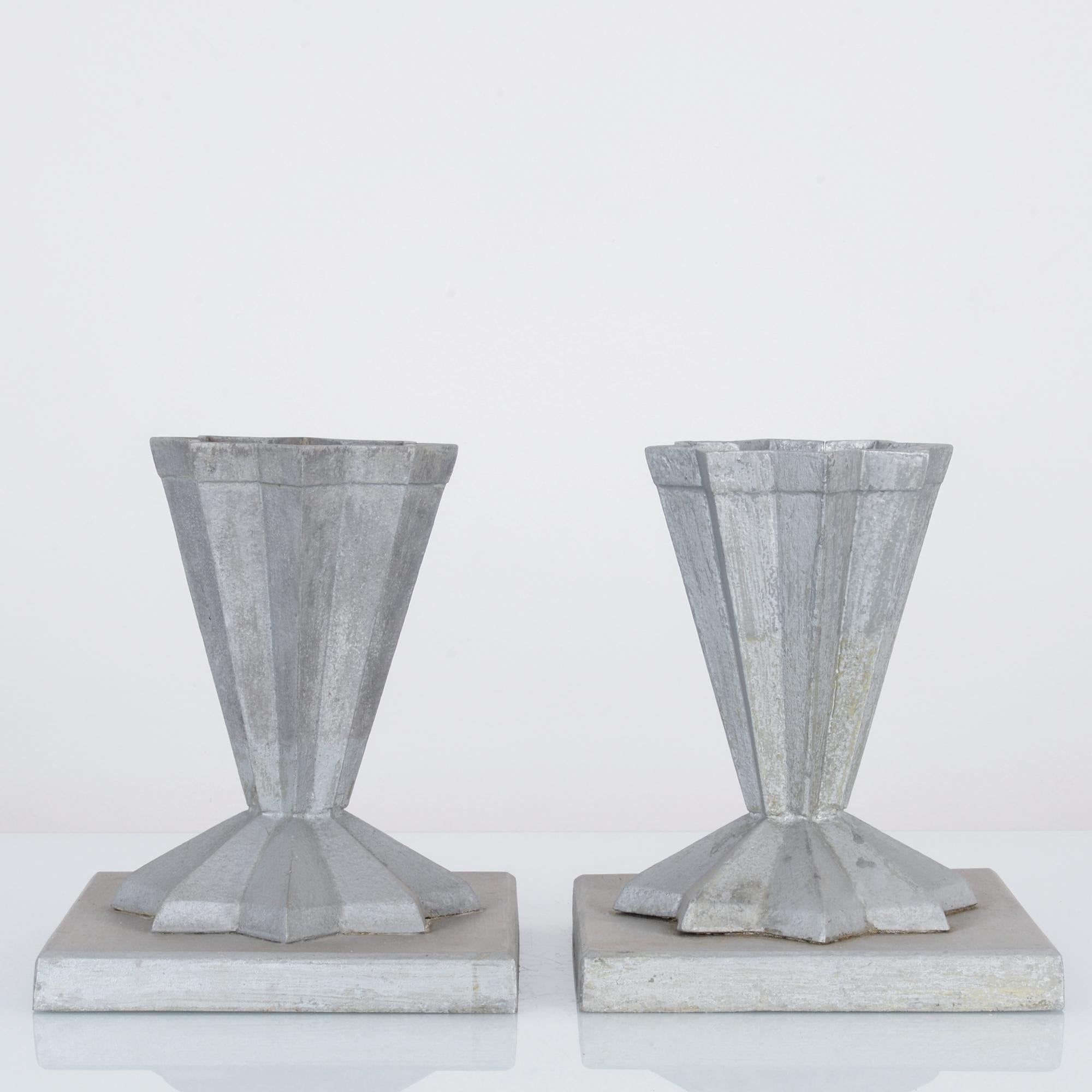 A pair of aluminum planters from France produced circa 1900. Standing on plinths in the shape of eight-point stars, these celestial decorations glitter as raised runes, buffed to a matte shine.