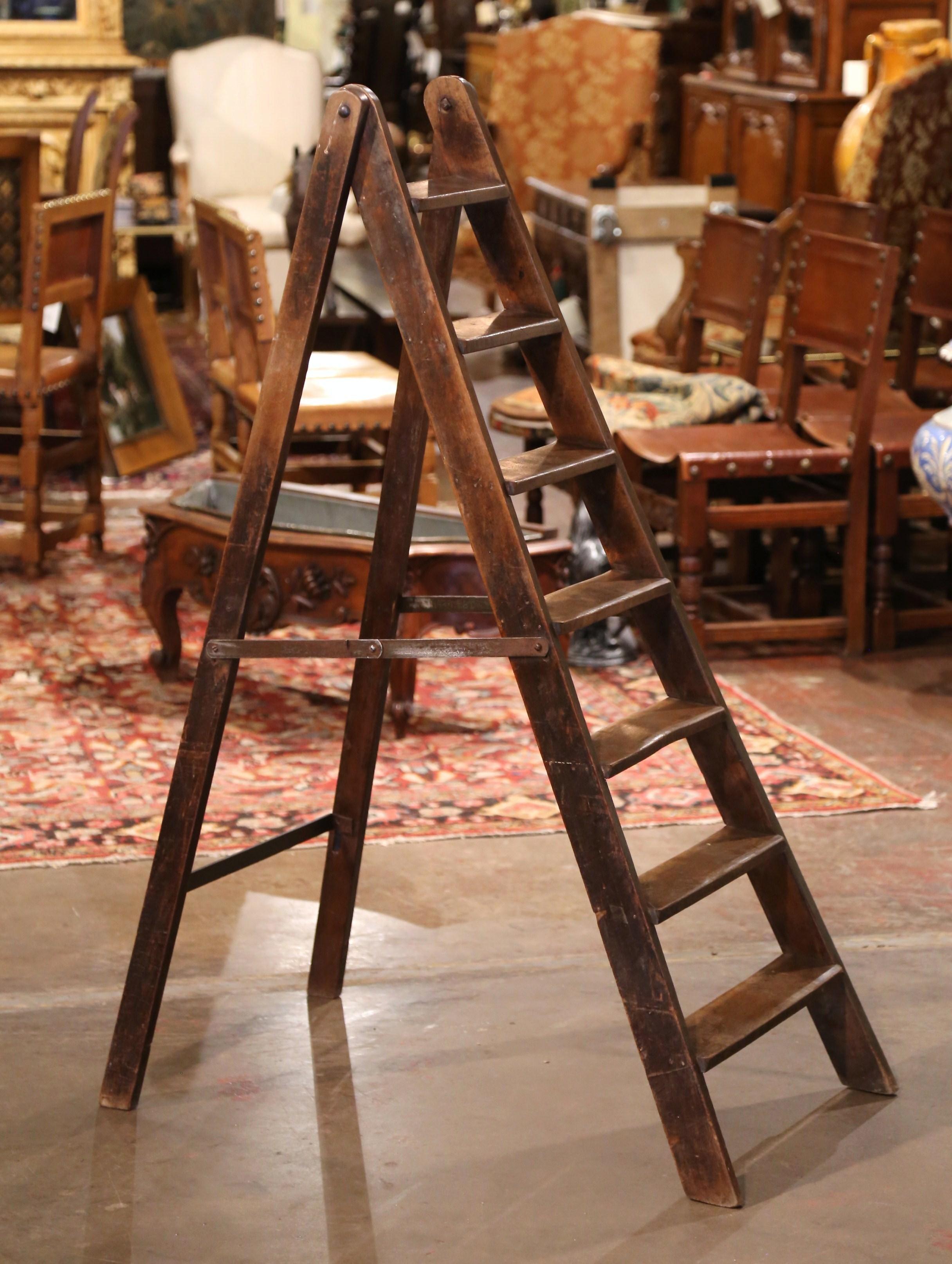 This elegant antique library ladder was created in Normandy France, circa 1920. Made of walnut, the sturdy step ladder features seven steps; it also includes a stabilizing iron beam opposite of the steps as well as two metal locking joints on both