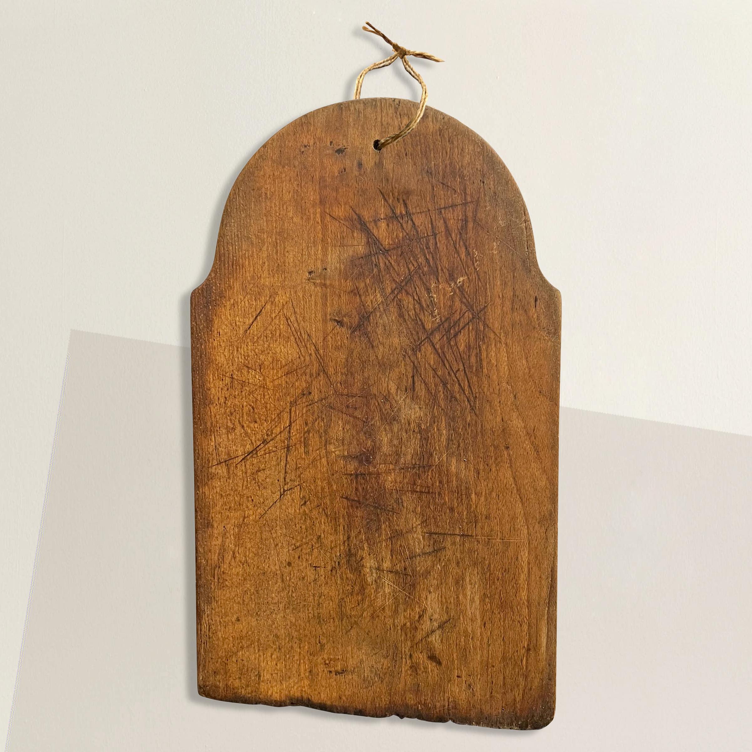 A wonderful early 20th century French cutting board with hundreds of knife marks, a jute string for hanging, and a patina that only time can bestow. Perfect for chopping vegetables and bread, or serving cheese and charcuterie at your next fête.