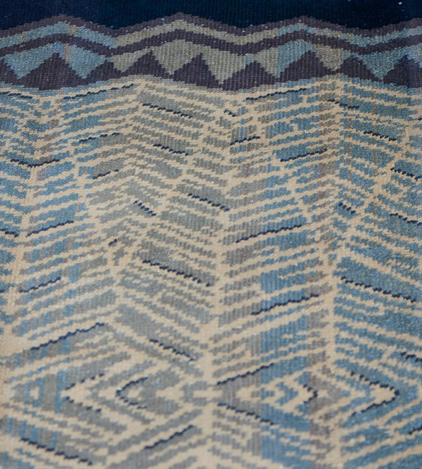 Esta alfombra deco francesa vintage tejida a mano tiene un campo gris azulado con un diseño general de delicado motivo de espiga con un prominente borde estilizado de chevron distal.

Las alfombras Decó europeas llegaron a principios del siglo XX en