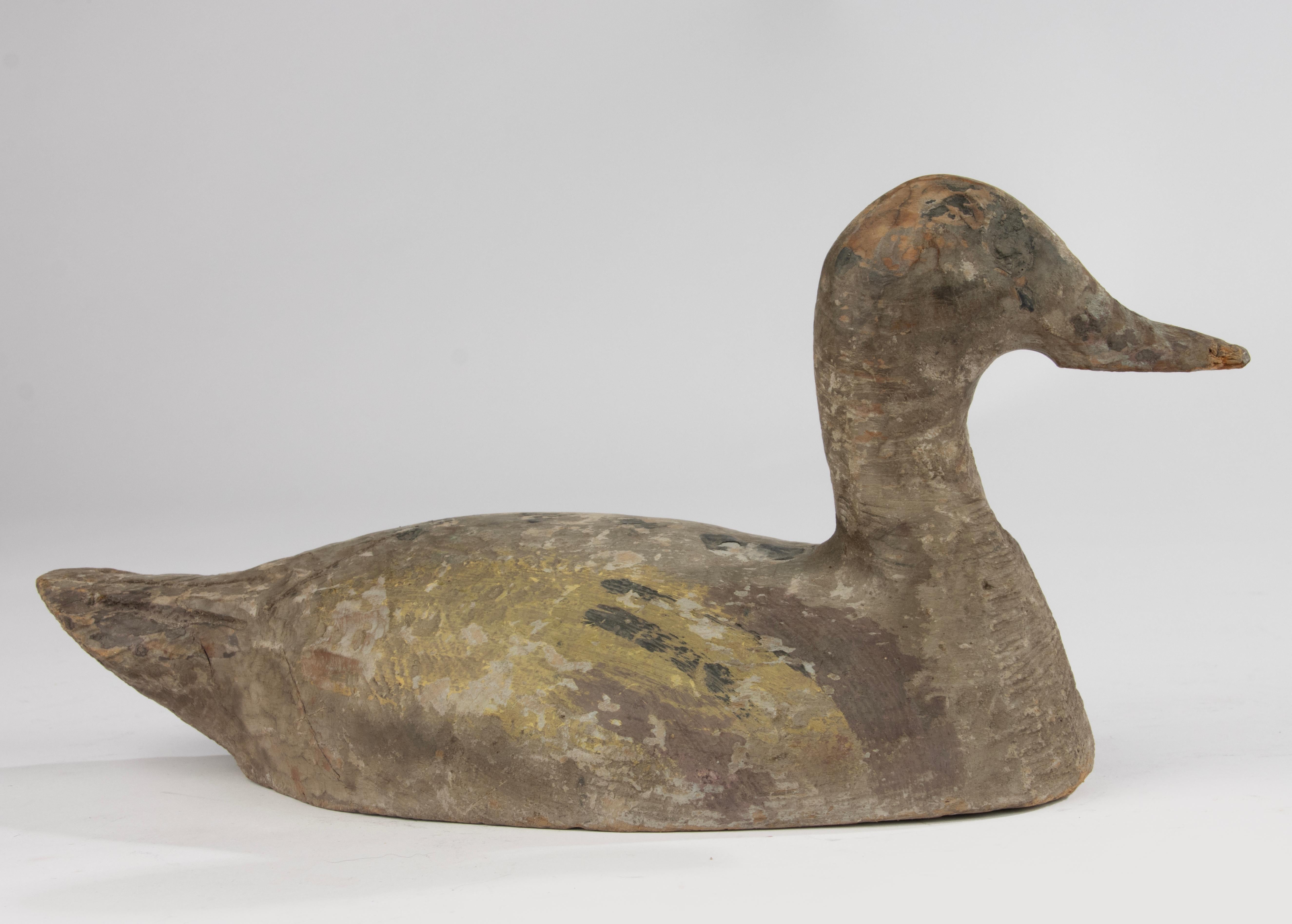 A charming hand-carved wooden decoy duck, likely French, dating from the early 20th century. This authentic working decoy shows wonderful traces of its original painted surface in soft, muted tones of ochre, brown, and grey — beautifully worn by