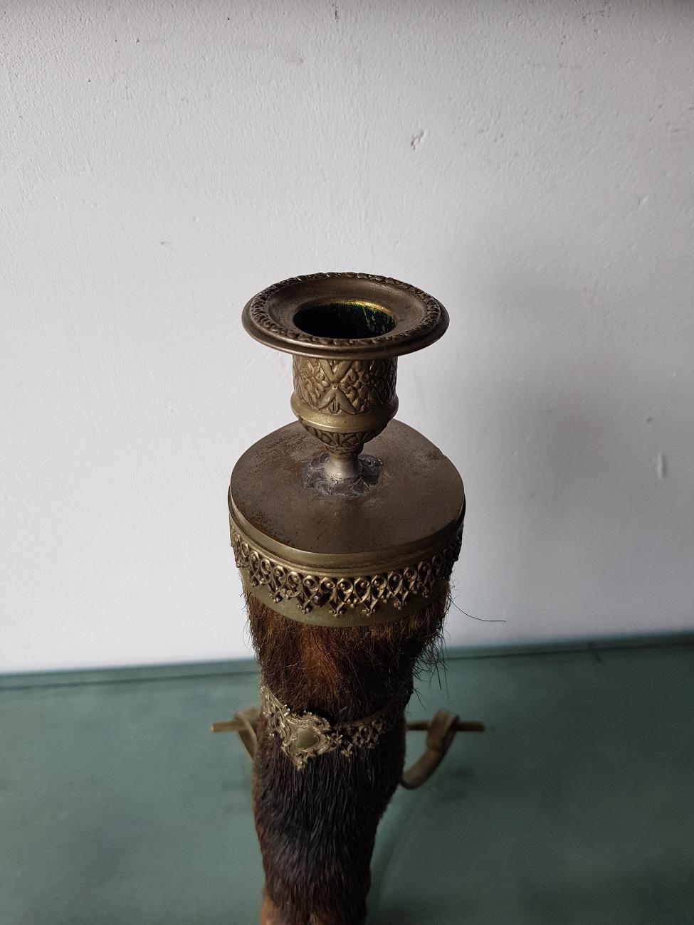 French deer leg made in to a candlestick with classic shaped metal ornaments, first half of the 20th century.

The measurements are,
Depth 13 cm/ 5.1 inch.
Width 12.5 cm/ 4.9 inch.
Height 25.5 cm/ 10 inch.
 