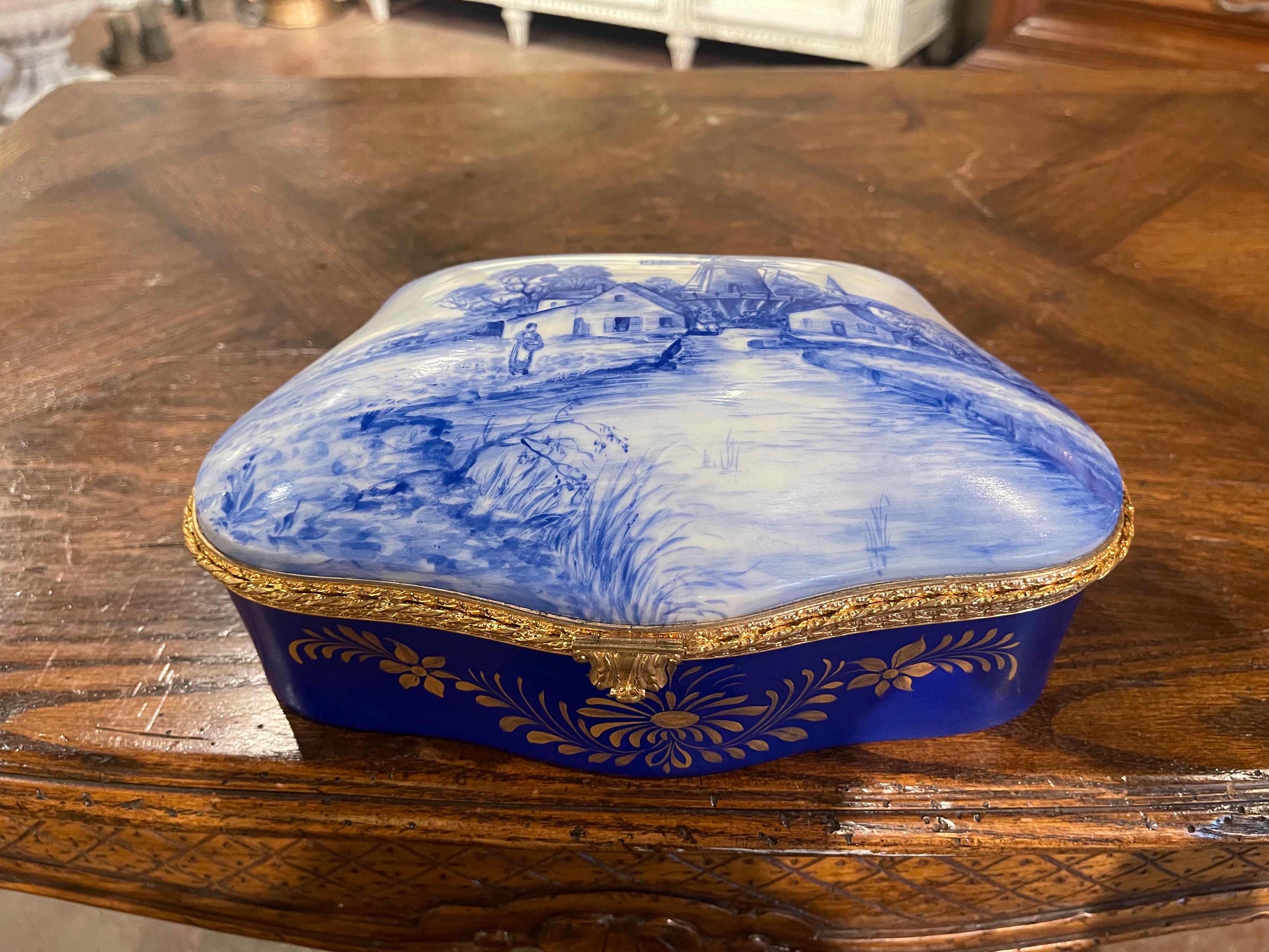 Decorate a master bathroom or powder room with this colorful antique jewelry box; crafted in France circa 1920 in the style of Delft, the porcelain bombe casket with cobalt blue and gilt border, features a traditional hand painted pastoral scene