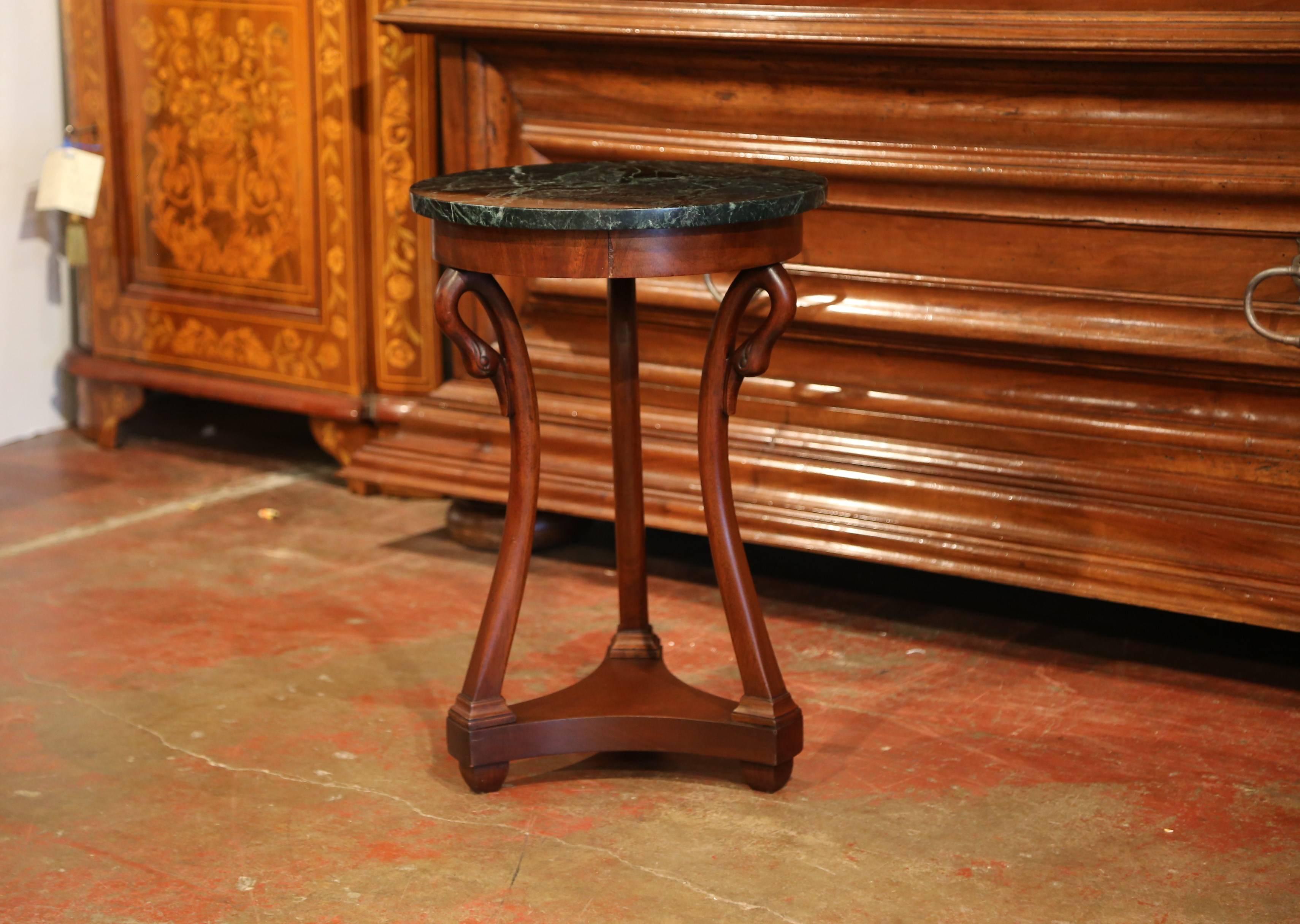 Elegant antique pedestal table from Paris, France; crafted circa 1920, the fruit wood table features three legs with swan head and neck decor over a bottom stretcher; the table is embellished by a round dark green marble top. The delicate end table