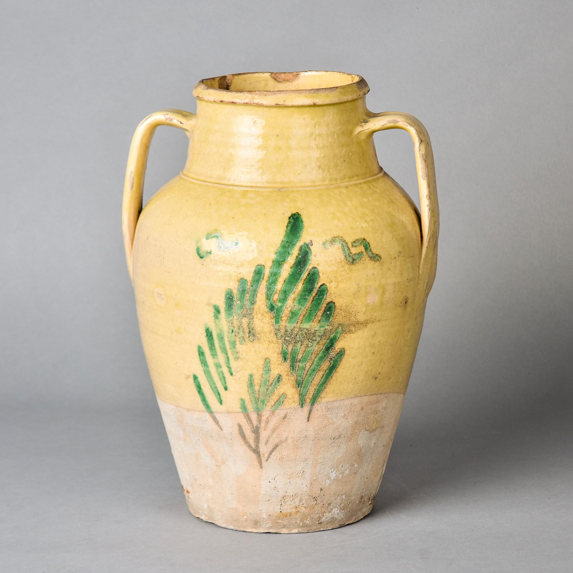 Trouvé en France, ce grand pot rustique traditionnel français datant de 1900 mesure plus de 13 pouces de haut et possède deux poignées incurvées. Il est recouvert d'une glaçure moutarde pâle accentuée par un motif de branches vertes. Quelques usures