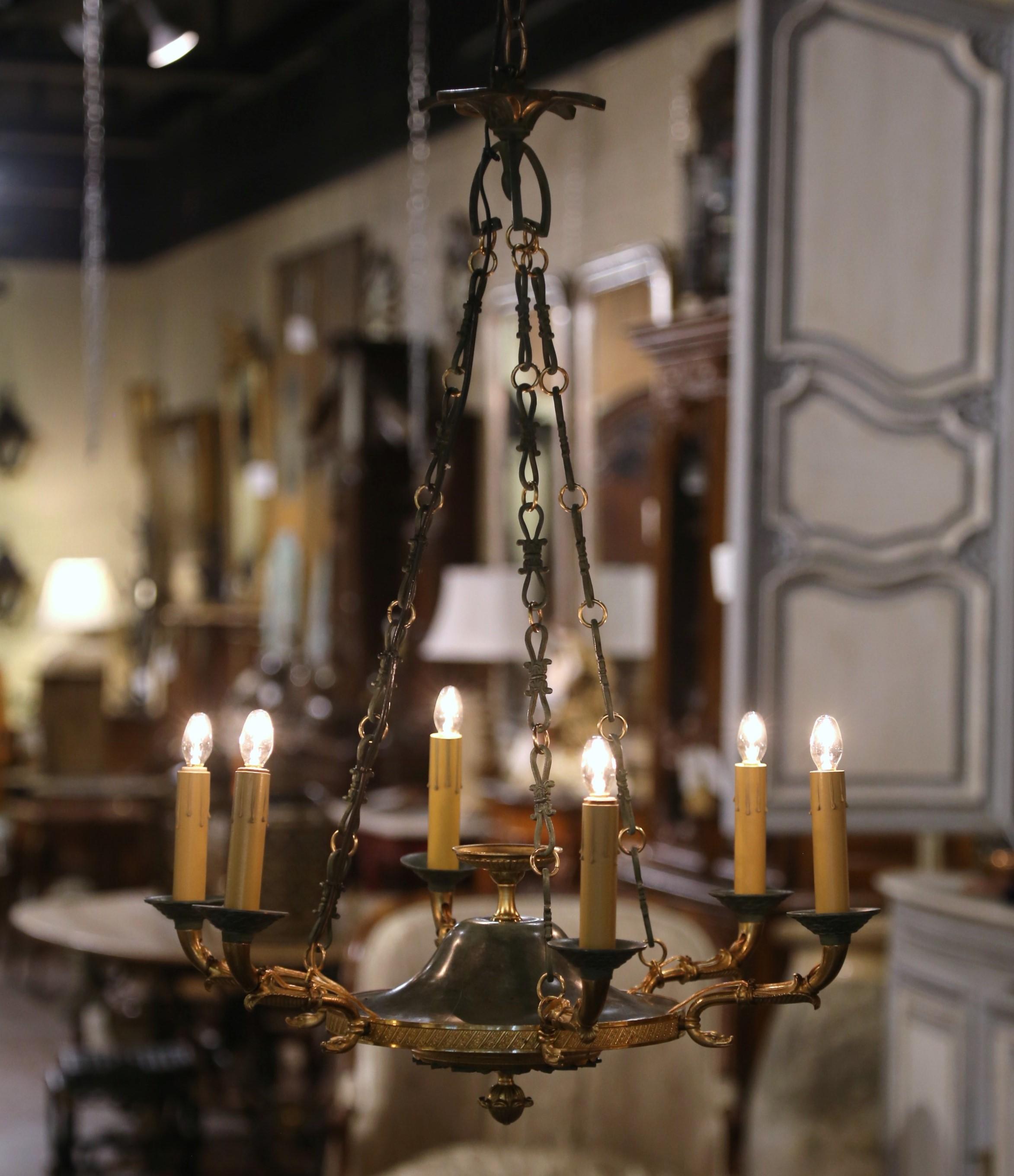 Illumina un ingresso o una toilette con questo sofisticato lampadario antico a sei luci. Realizzato a Parigi, in Francia, intorno al 1920 e costruito in bronzo, questo apparecchio di illuminazione presenta un piatto centrale dal design intricato,