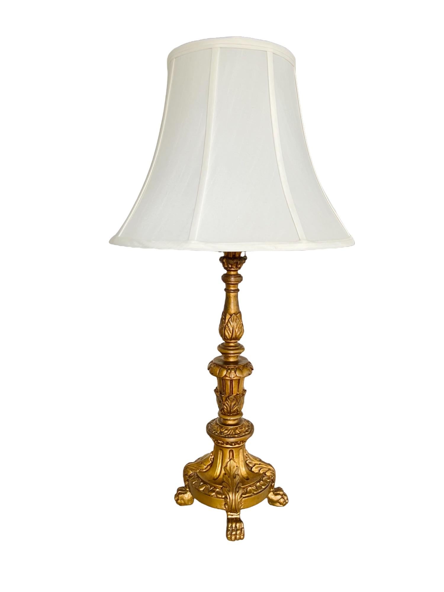 An early 20th century French Empire torchère style table lamp with shade. Gilded gessoed candlestick form metal body with paw foot mounted base. Two light sockets with individual pull cord operation. Off-white linen blend bell shade.

Dimensions: