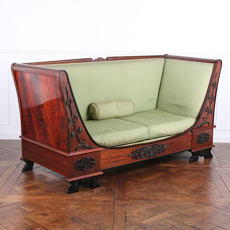 French Empire style settee or daybed in flame mahogany, the boldly-shaped arms and apron with carved ebonized details and trim, the whole raised on carved and ebonized paw feet.


 
