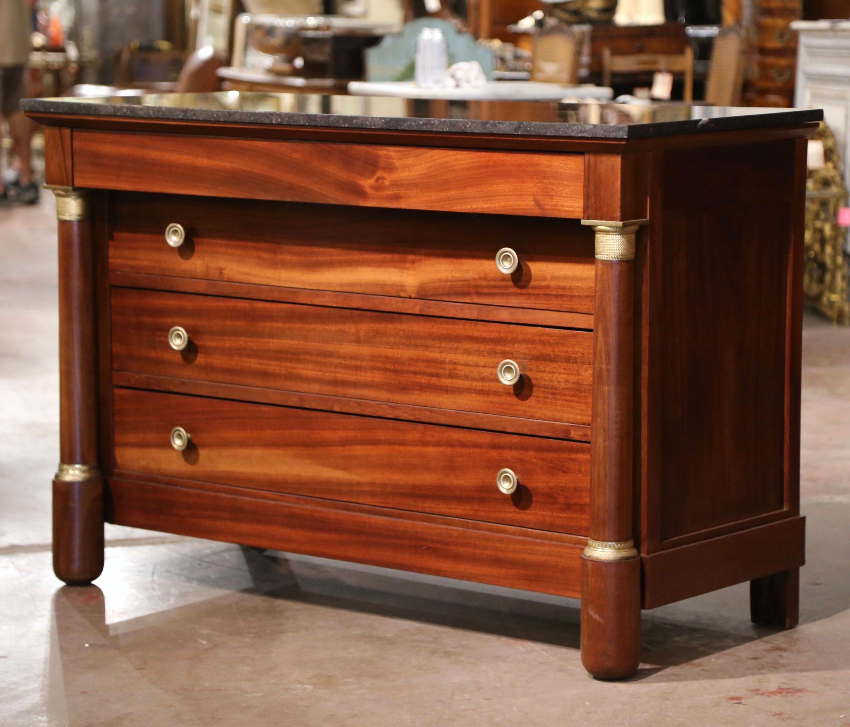 Decorate a living room or den with this elegant antique chest of drawers. Crafted in France, circa 1930, the traditional commode sits on carved columnar supports over a straight bottom plinth; the round columns are dressed with decorative bronze
