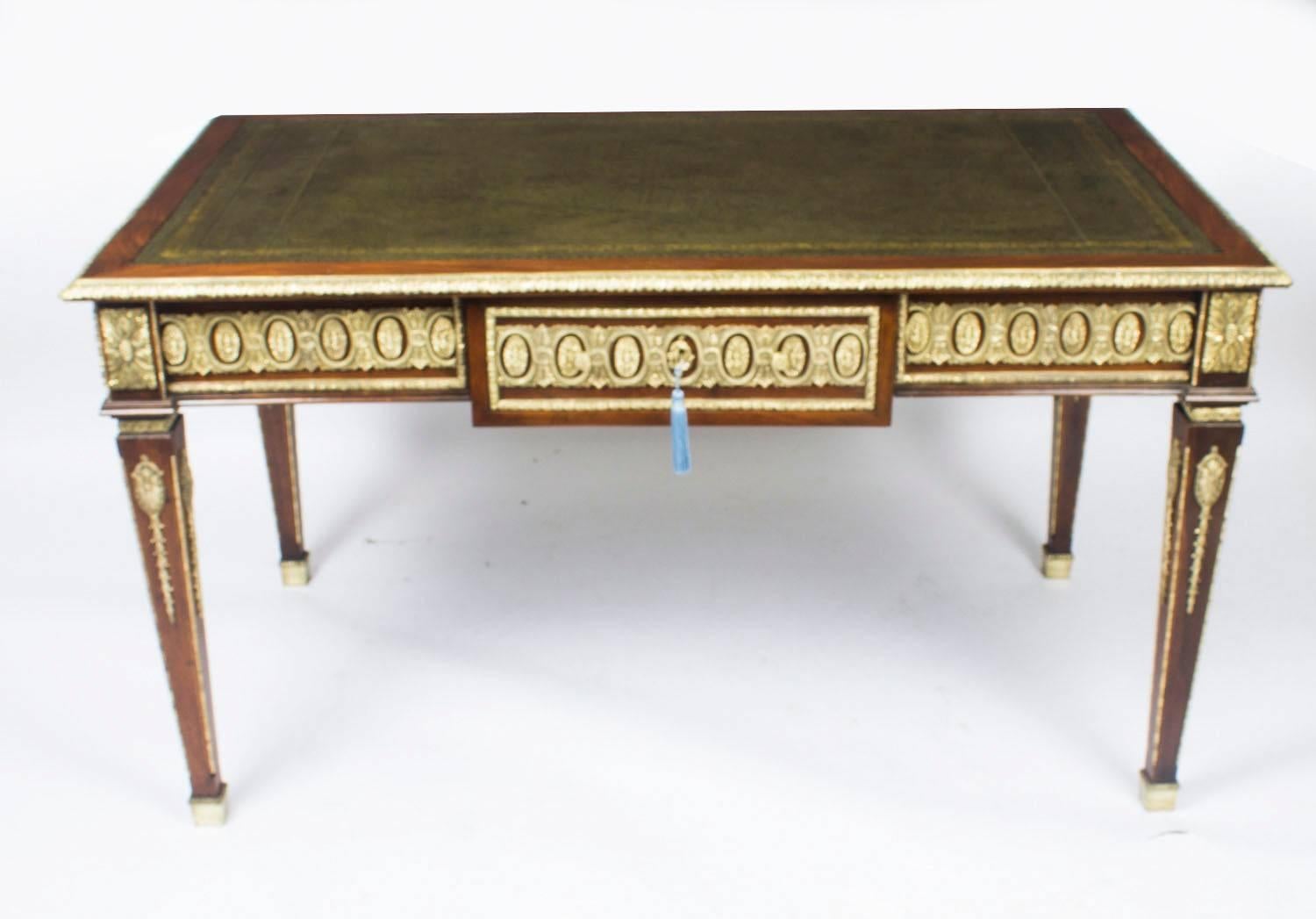 This is a fine antique French gilt-bronze mounted mahogany Empire style bureau plat, circa 1900 in date.
 
It has a green inset gold-tooled leather writing surface and the top has a very decorative gilt bronze border.

The frieze has a central