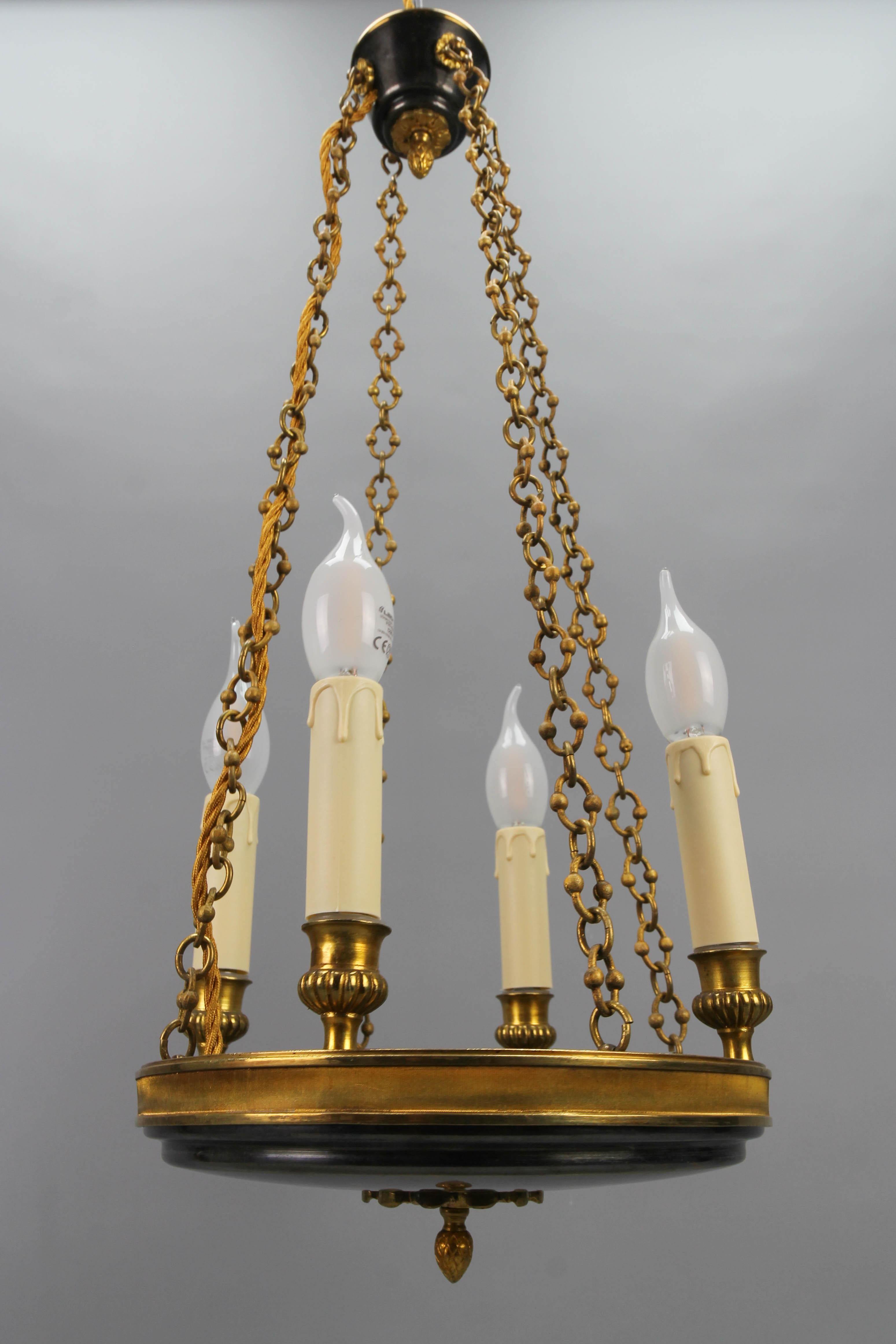 Early 20th Century French Empire Style Gilt Bronze Four-Light Chandelier.
An adorable and compact four-light pendant chandelier from the early 1900s. Hung on four ornate chains, gilt bronze details.
Four sockets for E14-size light bulbs.
Dimensions: