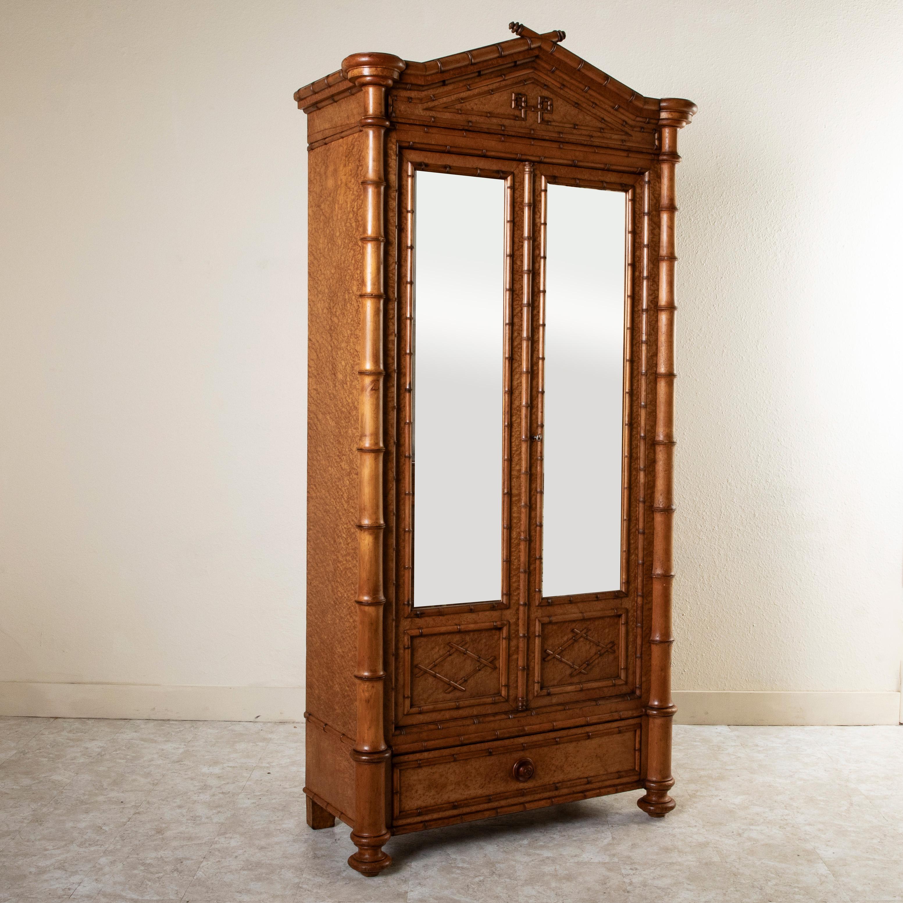 This turn of the twentieth century French faux bamboo armoire stands at an impressive height of eight feet and is constructed of cherrywood and birdseye maple. Its finely detailed bamboo pieces, harmoniously laid in a uniform pattern, blend with the
