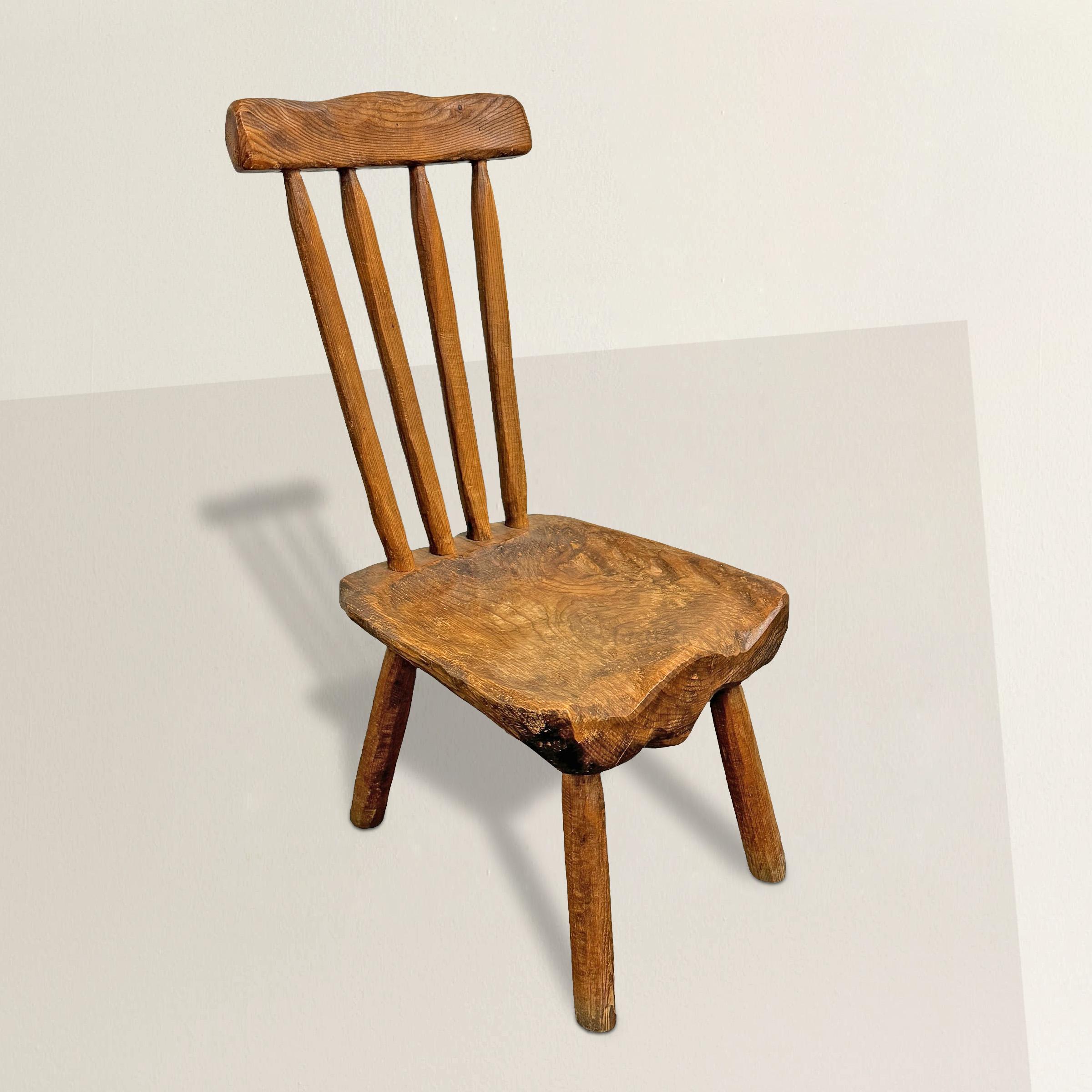 This early 20th-century French Folk Art side chair, hand-carved from pine, embodies a modernist spirit with its playful silhouette and chunky saddle seat. What truly sets it apart is its remarkable patina, a testament to years of loving