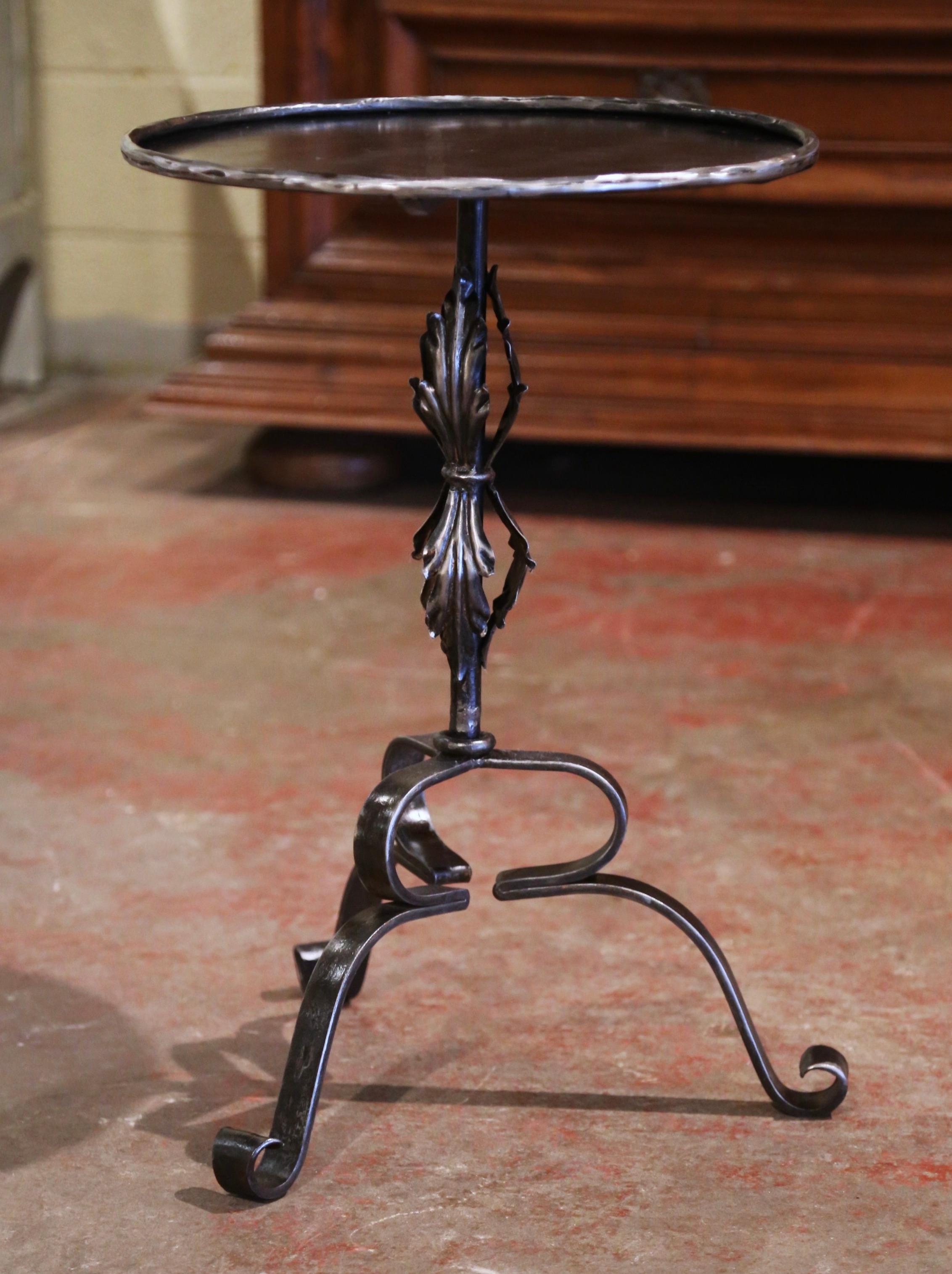 This elegant, antique Gothic pedestal table was crafted in Southern France, circa 1920. The intricate martini table stands on three forged curved legs ending with scrolled feet, over a central pedestal stem embellished with acanthus leaf motifs. The