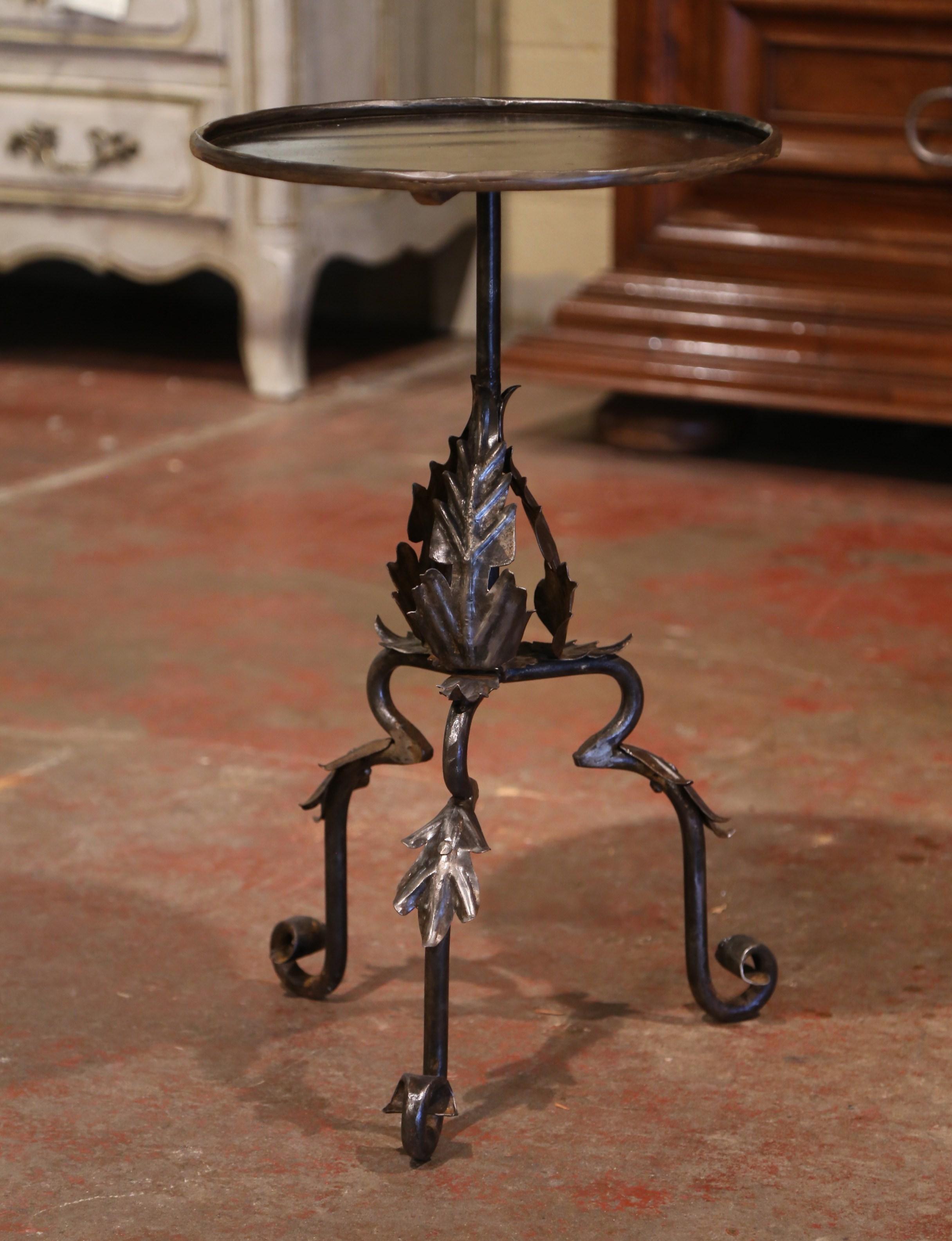 This elegant, antique Gothic pedestal table was crafted in Southern France, circa 1920. The intricate martini table stands on three forged legs embellished with acanthus leaves, over a central pedestal stem decorated with leaf motifs. The serving