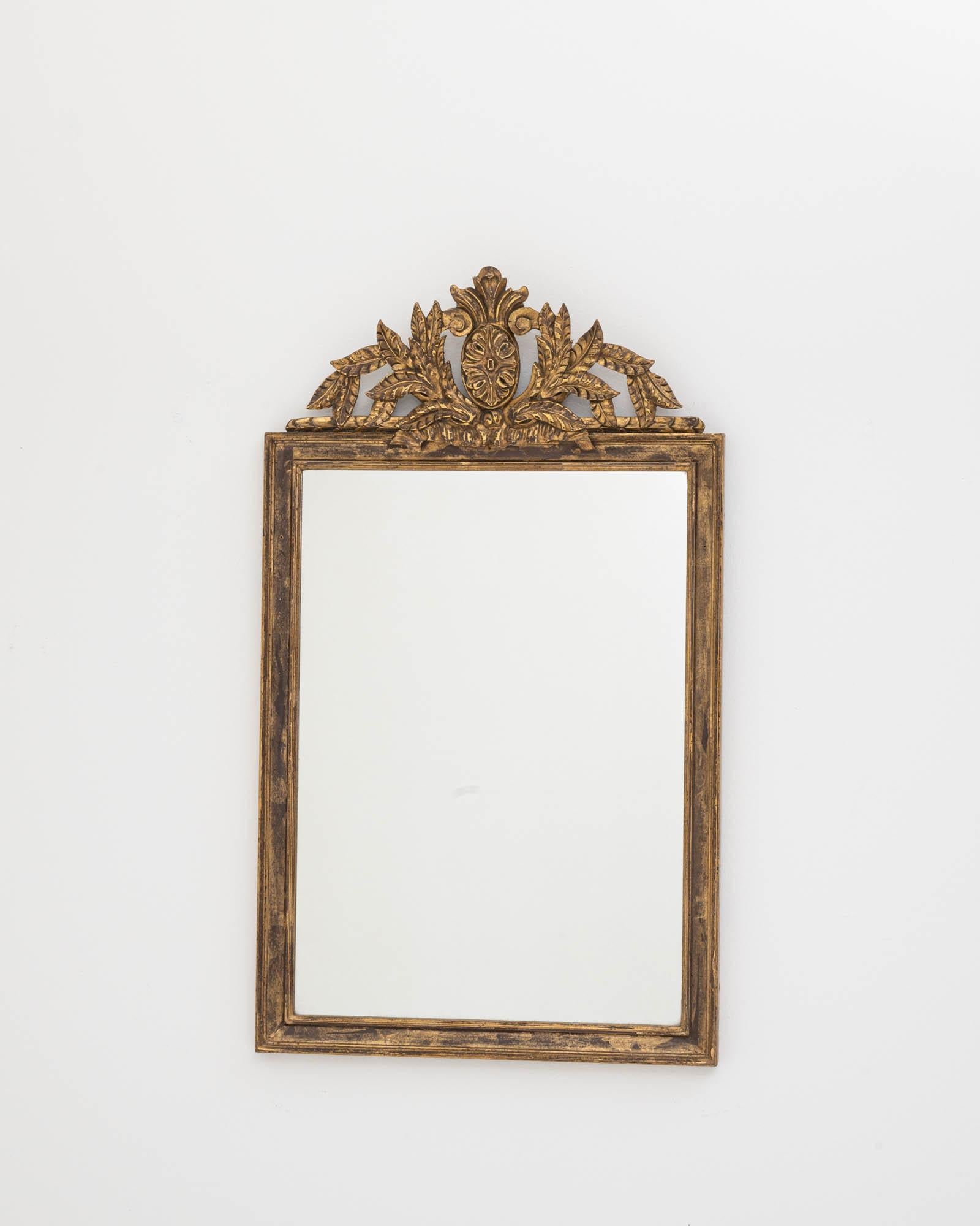 Presenting a magnificent piece of history with this Early 20th Century French Gilded Wood Mirror. Drenched in the splendor of its time, this mirror is an epitome of classic elegance. Its exquisite gilded frame, adorned with intricate foliage and an