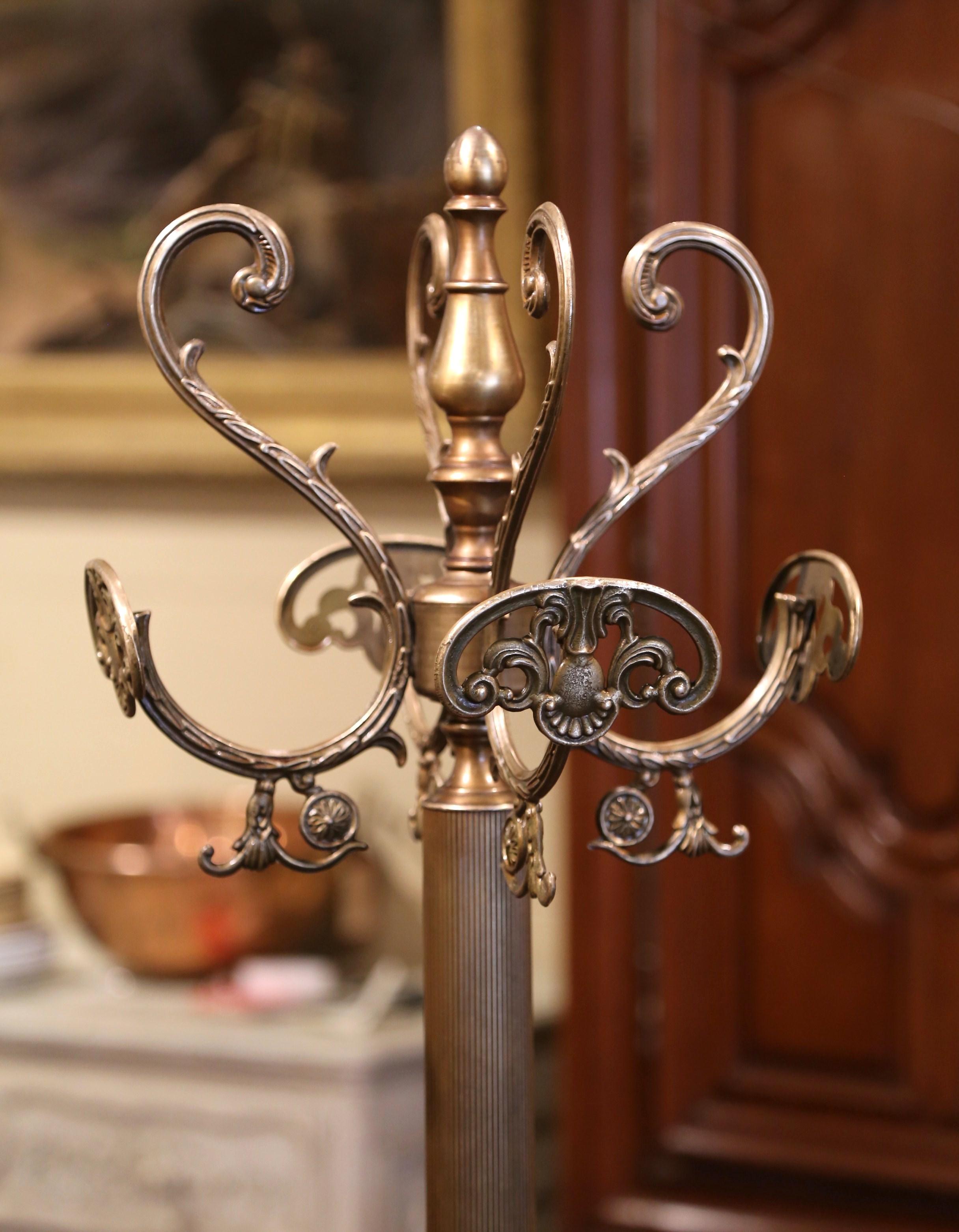This Italian gilt brass and metal hall tree was crafted in France circa 1920, standing on scrolled feet over a reeded central stem with foliate and scroll work accents, the coat rack features a swivel top with four double arms ending in hat and coat