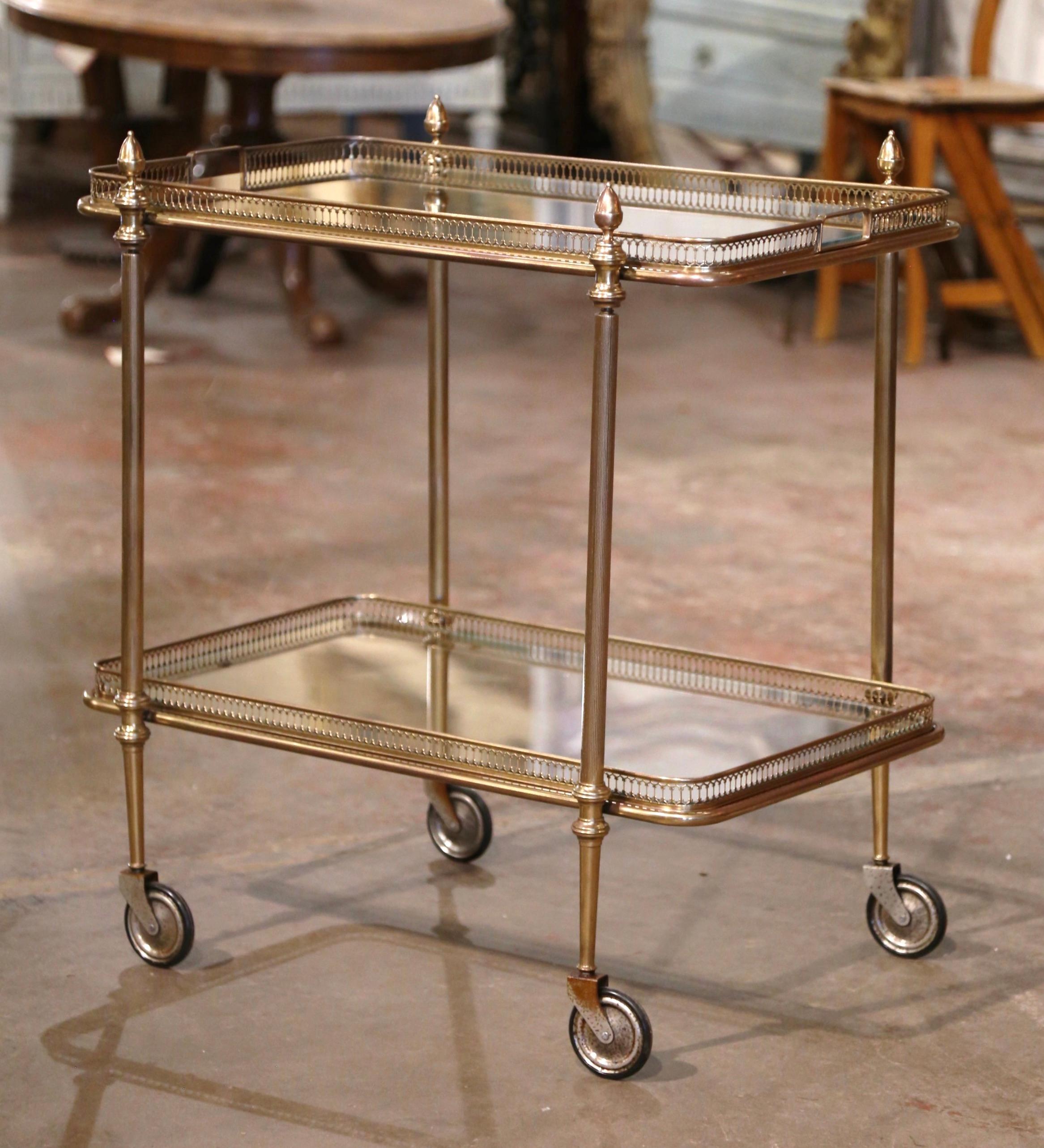 This elegant vintage rolling bar cart was created in France, circa 1930. Built in brass and rectangular in shape, the two-tier plateau trolley stands fluted legs topped with decorative finials, and ending with small round wheels and rubber tires.