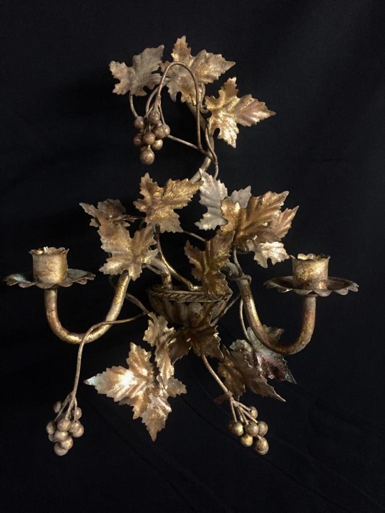 A beautiful pair of French early 20th century gilt sconces, each one holds 2 candles with grape vine leaves entwined around each arm and creating a decorative back. Leaf and grape arrangement is slightly different on each sconce making each