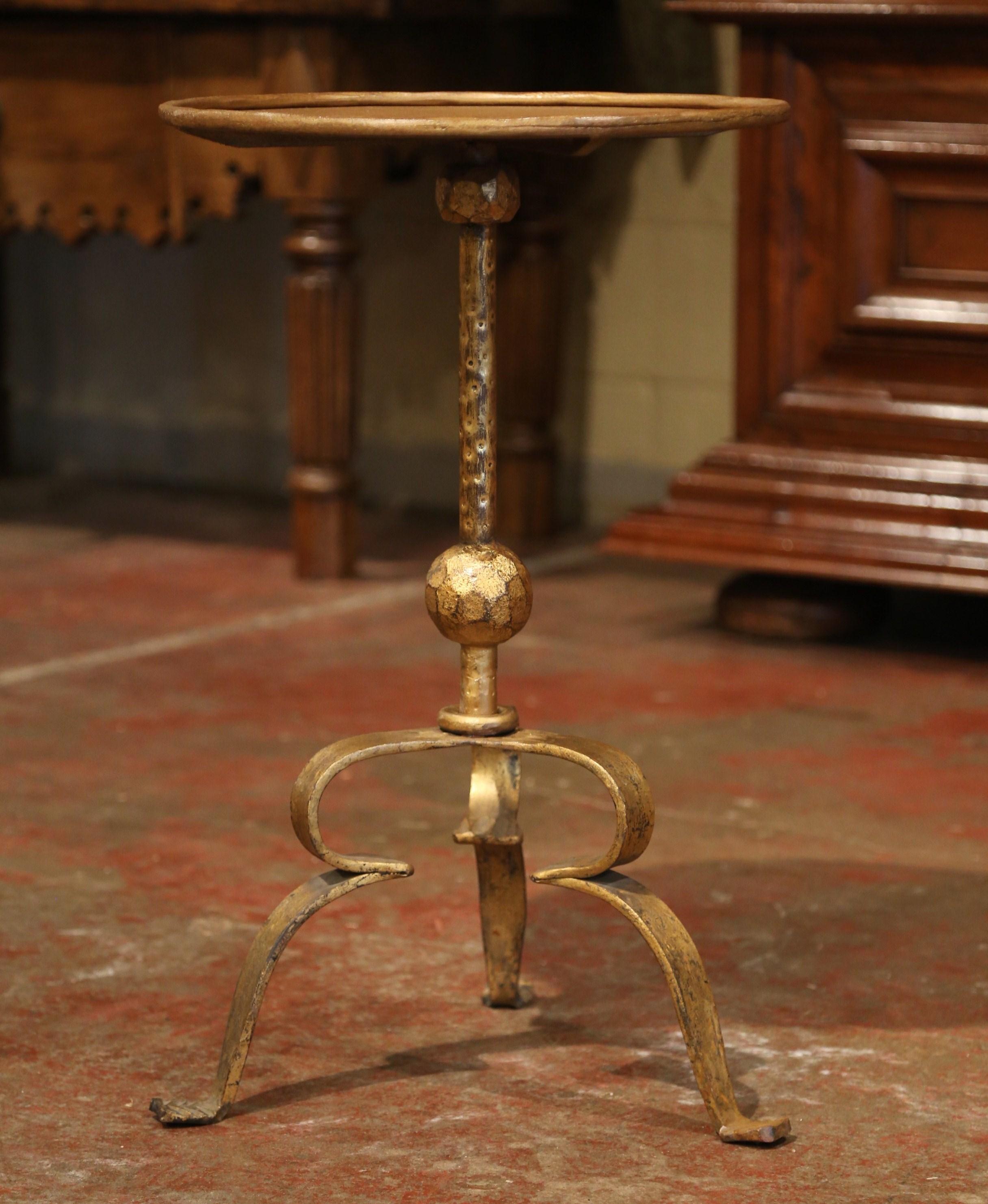 This elegant, antique pedestal table was crafted in Southern France, circa 1920. The intricate martini table features a forged central pedestal stem embellished with a central decor over three hammered scroll feet. The serving table is topped with a