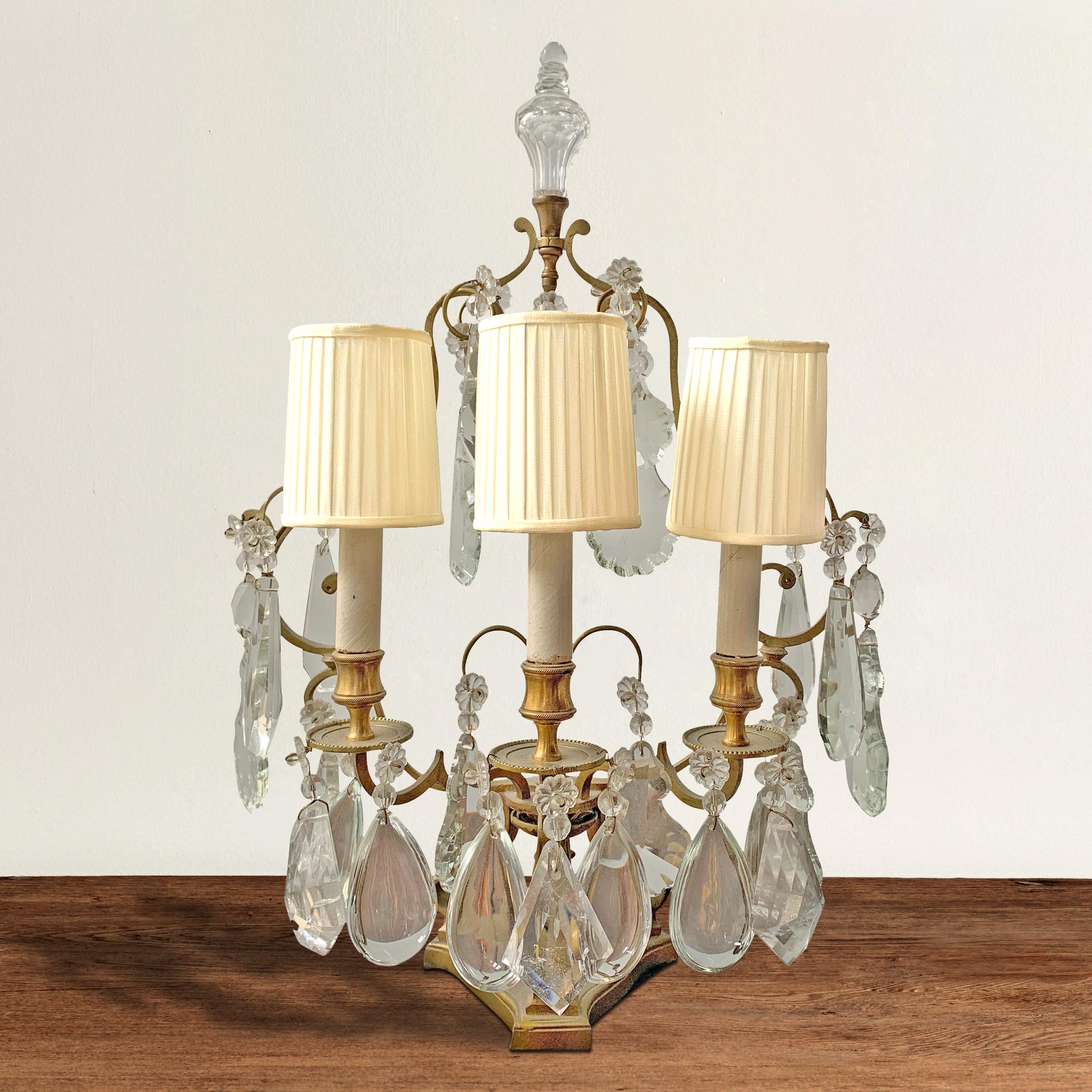 A wonderful early 20th century French gilt bronze three-light girandole with pleated silk shades, and dripping with handcut rock crystal and man-made crystal pendalogues. Fixture is three sided, and designed to be placed against near or against a