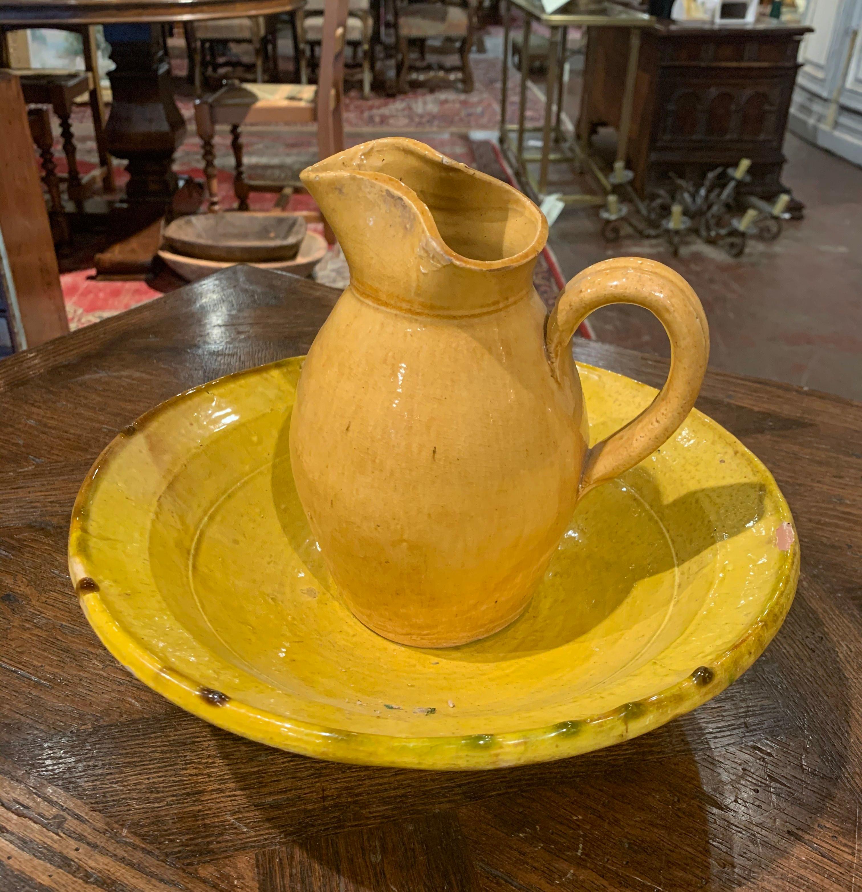 This antique water pitcher with matching bowl were crafted in Provence, circa 1930; typically used to freshen up in the morning, the decorative pottery set have a glazed covering in the mustard palette. Both earthenware pieces are in excellent
