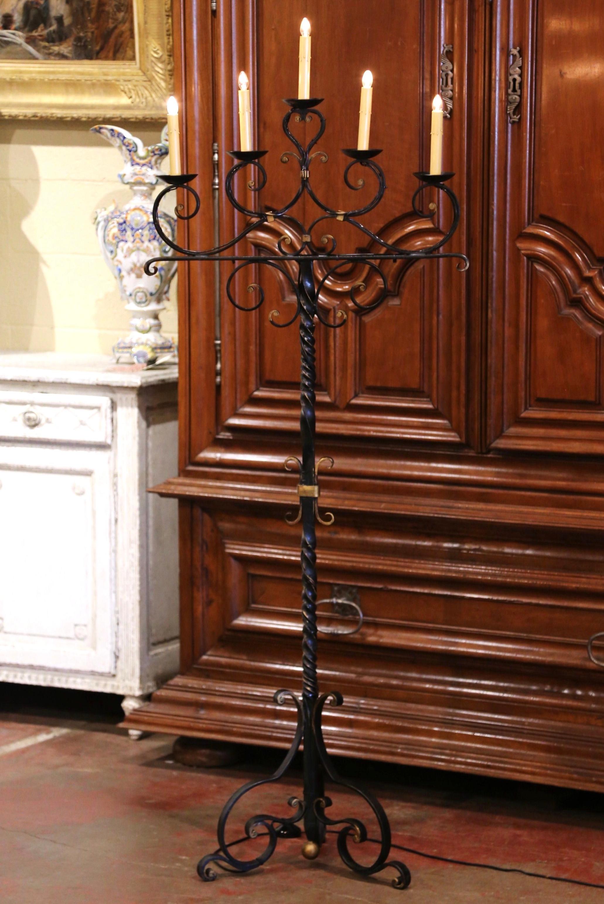 This elegant antique fixture was crafted in southern France, circa 1920. The Gothic candelabra lamp stands on a twisted, forged stem with three curved legs ending with scrolled feet. The cathedral lamp with scrolled decor between each arm, features