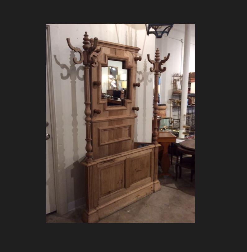 Found in the South of France, this Antique Hall Tree is from the early 20th century. It features a mirror, two arms for hanging coats, six pegs for hanging hats and a zinc lined umbrella holder. The wood finish is natural, which allows it to to mix