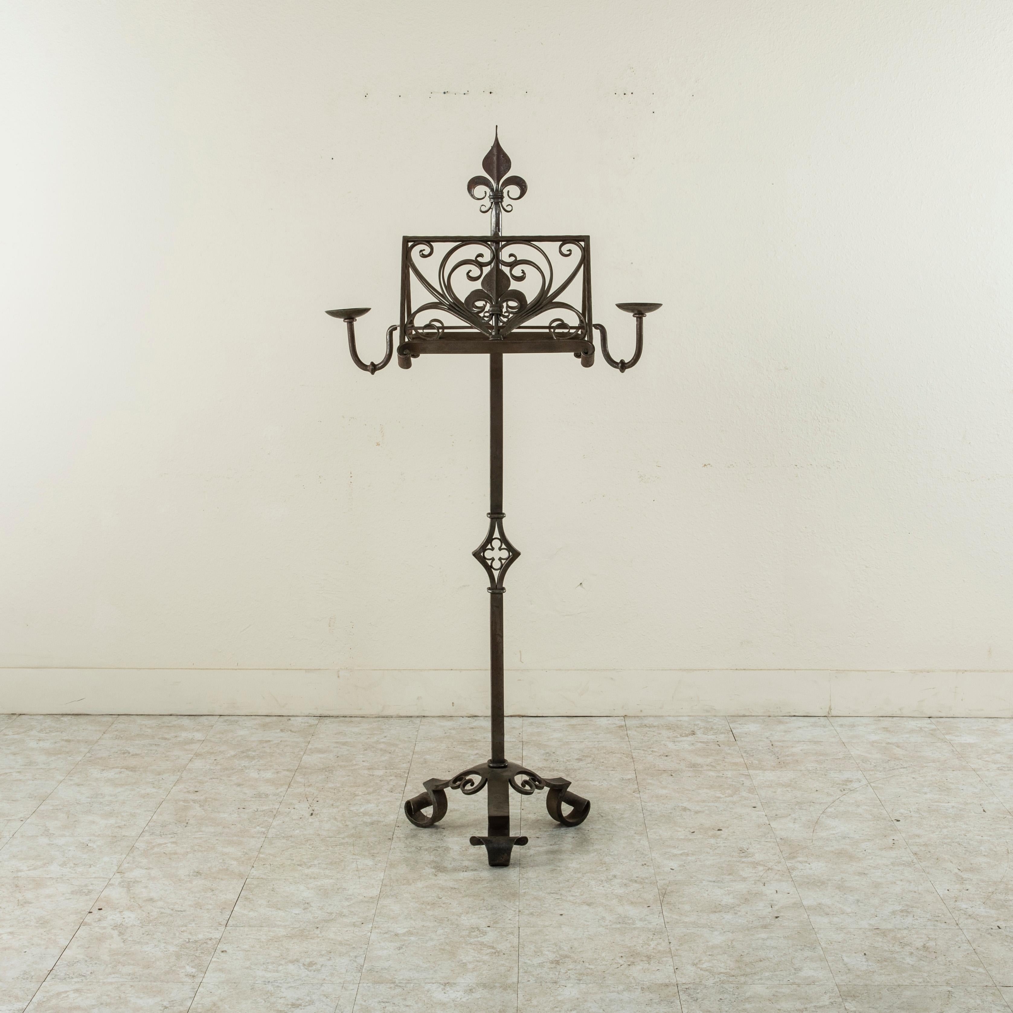 Originally used in a church, this impressive French hand-forged iron music stand is designed so that a musician can stand on each side. Candleholders extend on the left and right to light sheet music and a central fleur-de-lys appoints the top. The