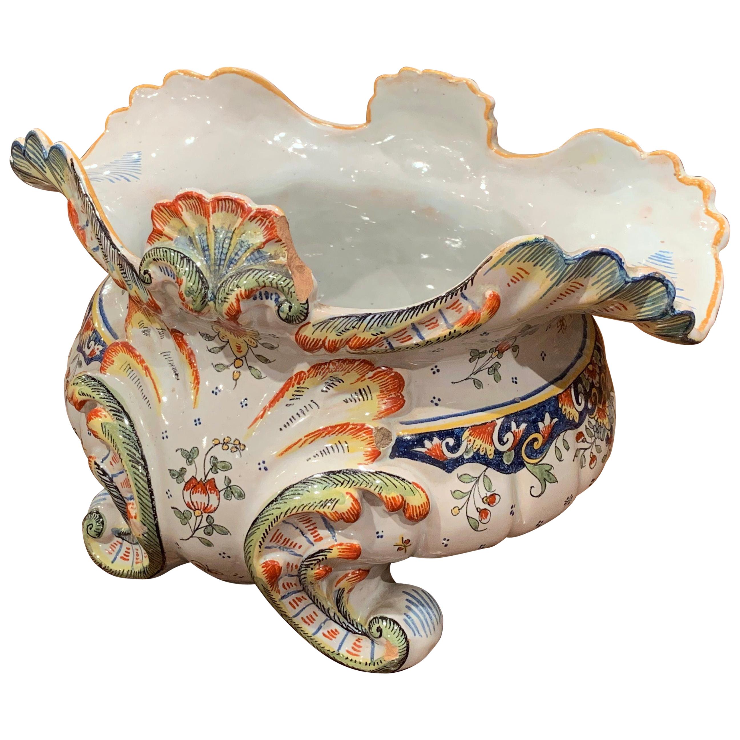 Decorate a table or a buffet with this elegant antique planter. Crafted in Rouen, Normandy, France circa 1920, the colorful cachepot sits on four scroll feet and features a scalloped rim with shell motifs. The piece is hand painted with floral and