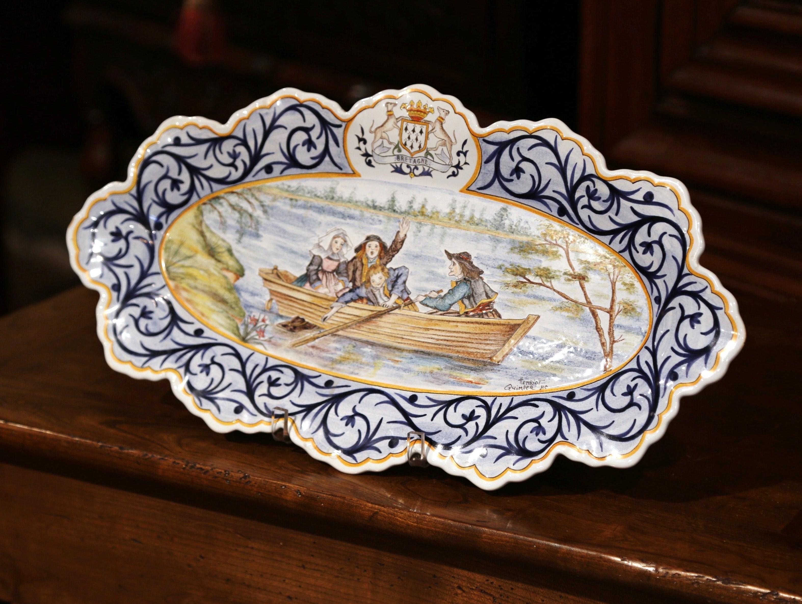 Decorate your kitchen or breakfast room with this important ceramic wall charger; crafted in Quimper by Henriot, circa 1920 the faience oval plate with blue border and a centre coat of arms of 
