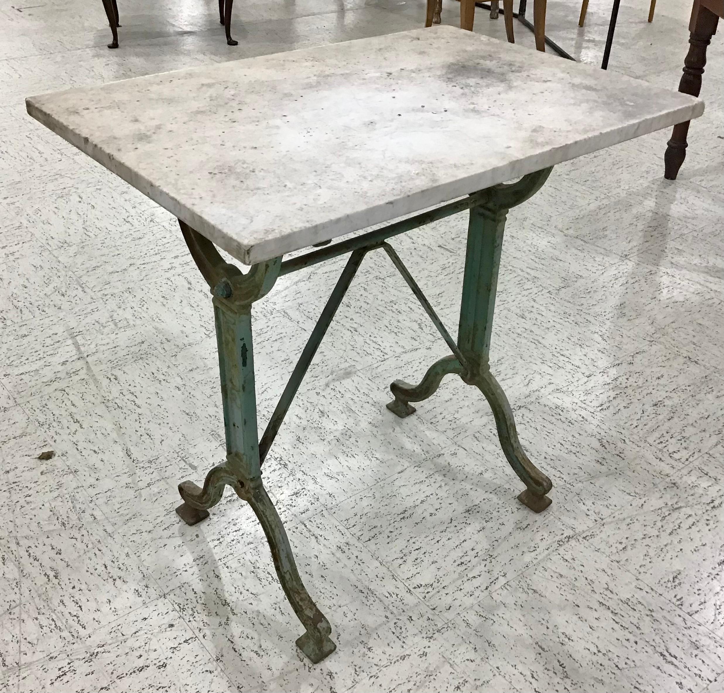 Originally used in a French brasserie during the early 20th century, this cast iron bistro table or cafe table features the original white marble top. Scrolled iron legs support the top and are joined by an X-stretcher that provides additional