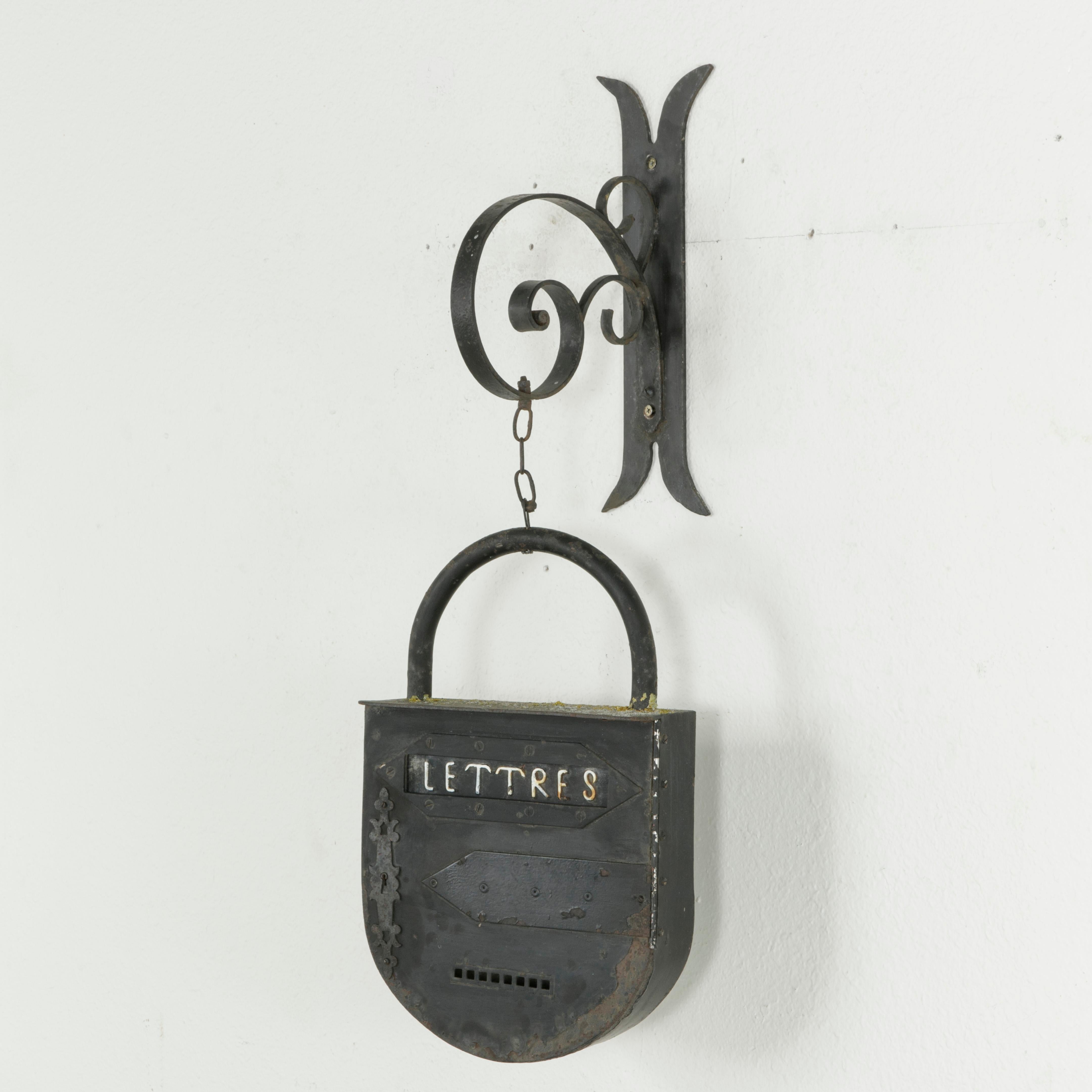 This large mid-20th century French iron padlock is marked Lettres in white or Letters and was once used as a mailbox. Hanging from a hand forged iron bracket, this piece now serves as a decorative object.