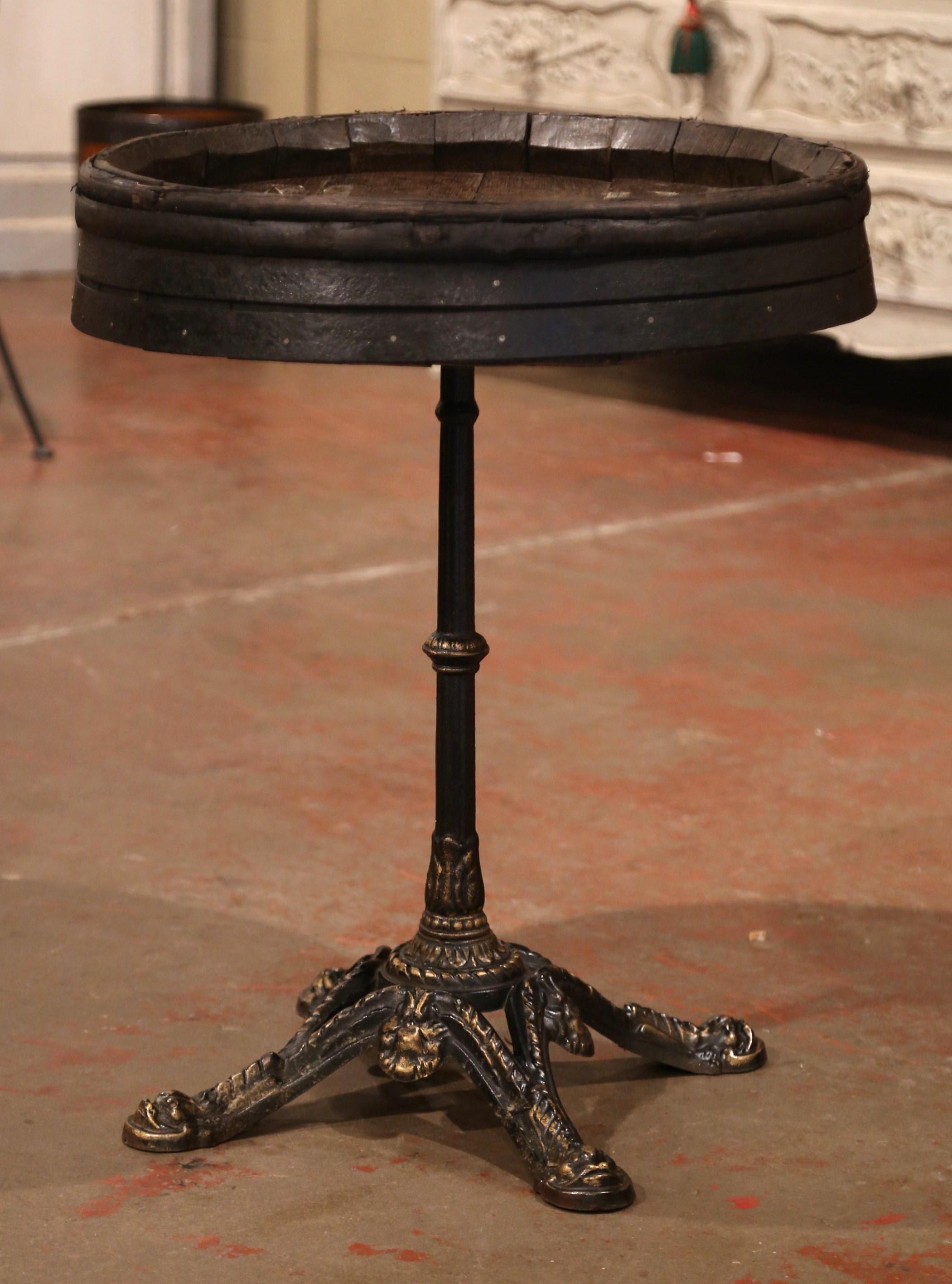 Decorate a wine cellar with this antique wine table; created in the wine Bordeaux region of France, circa 1920, the table features an black iron pedestal base with paw feet and embellished with gilt accents. The surface is a wine barrel top made of