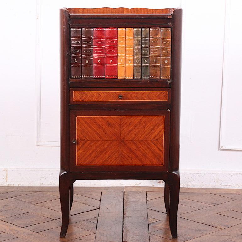 An unusual and pretty French two-door cabinet, the upper door with 'faux' books, the lower door with book-matched kingwood bordered with mahogany and boxwood stringing between. Similar veneer patterning to the small drawer as well as the case sides