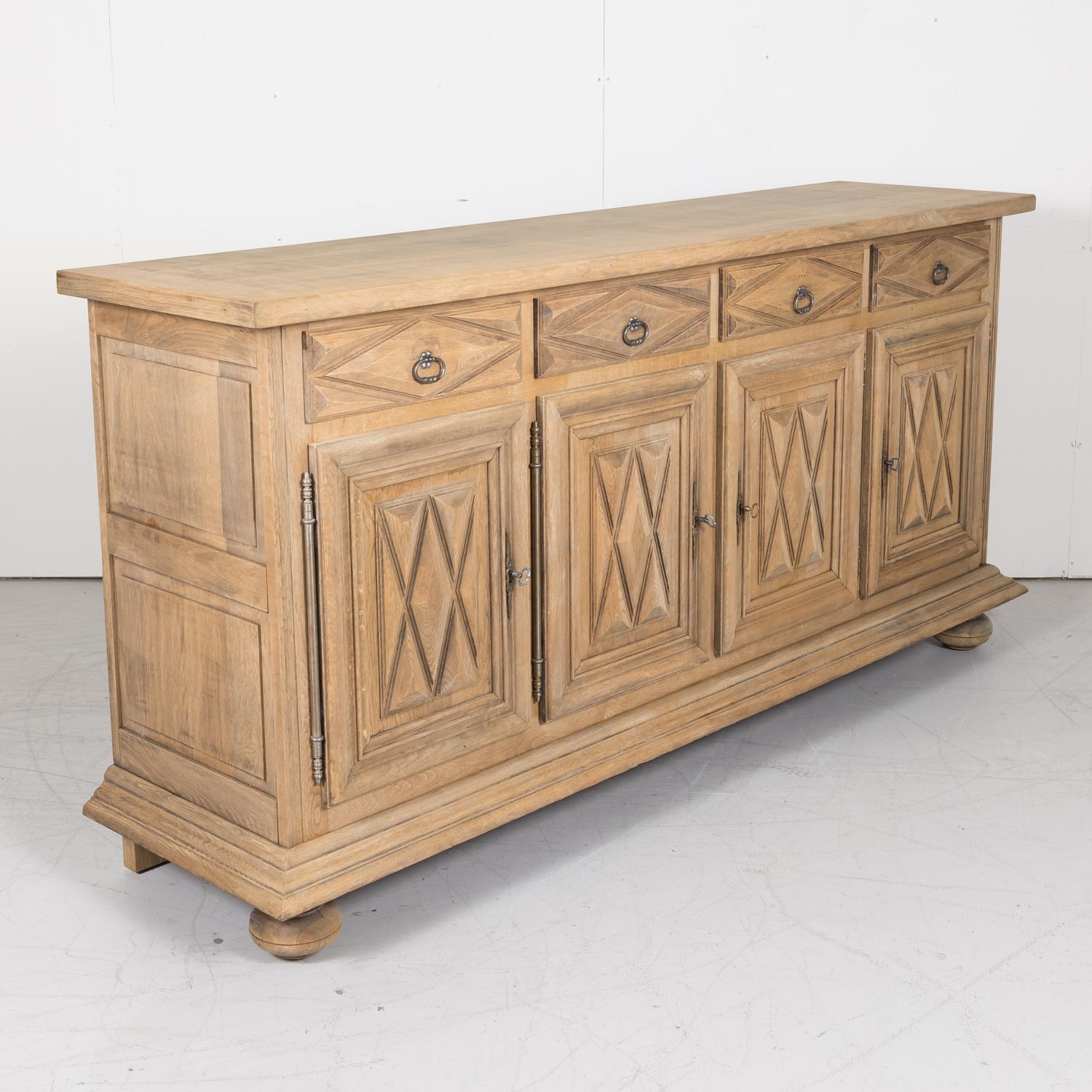 Early 20th century French Louis XIII style bleached enfilade buffet handcrafted of solid old growth oak by talented artisans in Toulouse, circa 1920s, having a rectangular top above four carved drawers with lozenge motifs over four doors with raised