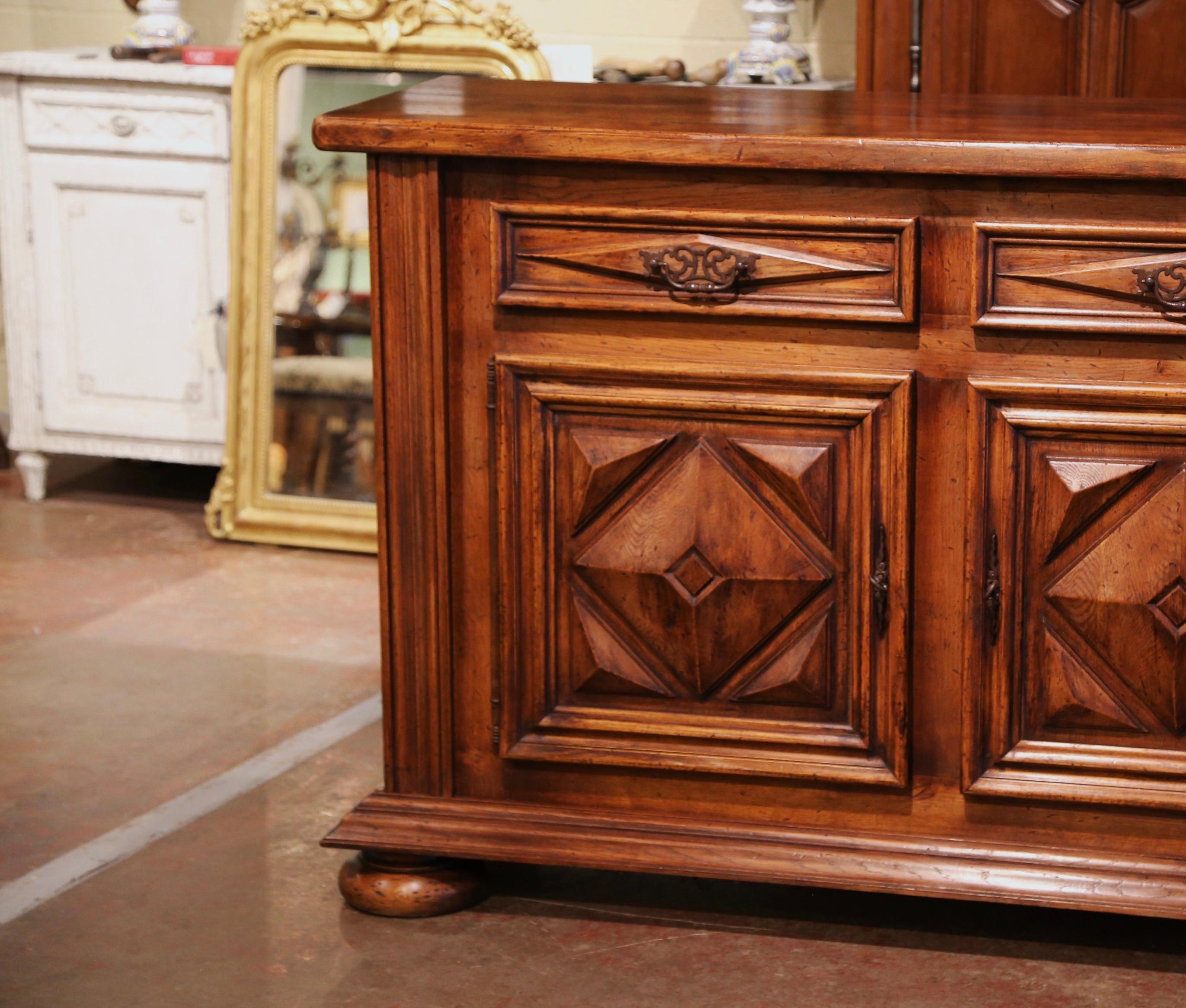Carved in southern France circa 1920, this elegant antique enfilade stands on bun feet over a thick plinth apron. The cabinet features three carved drawers with 
