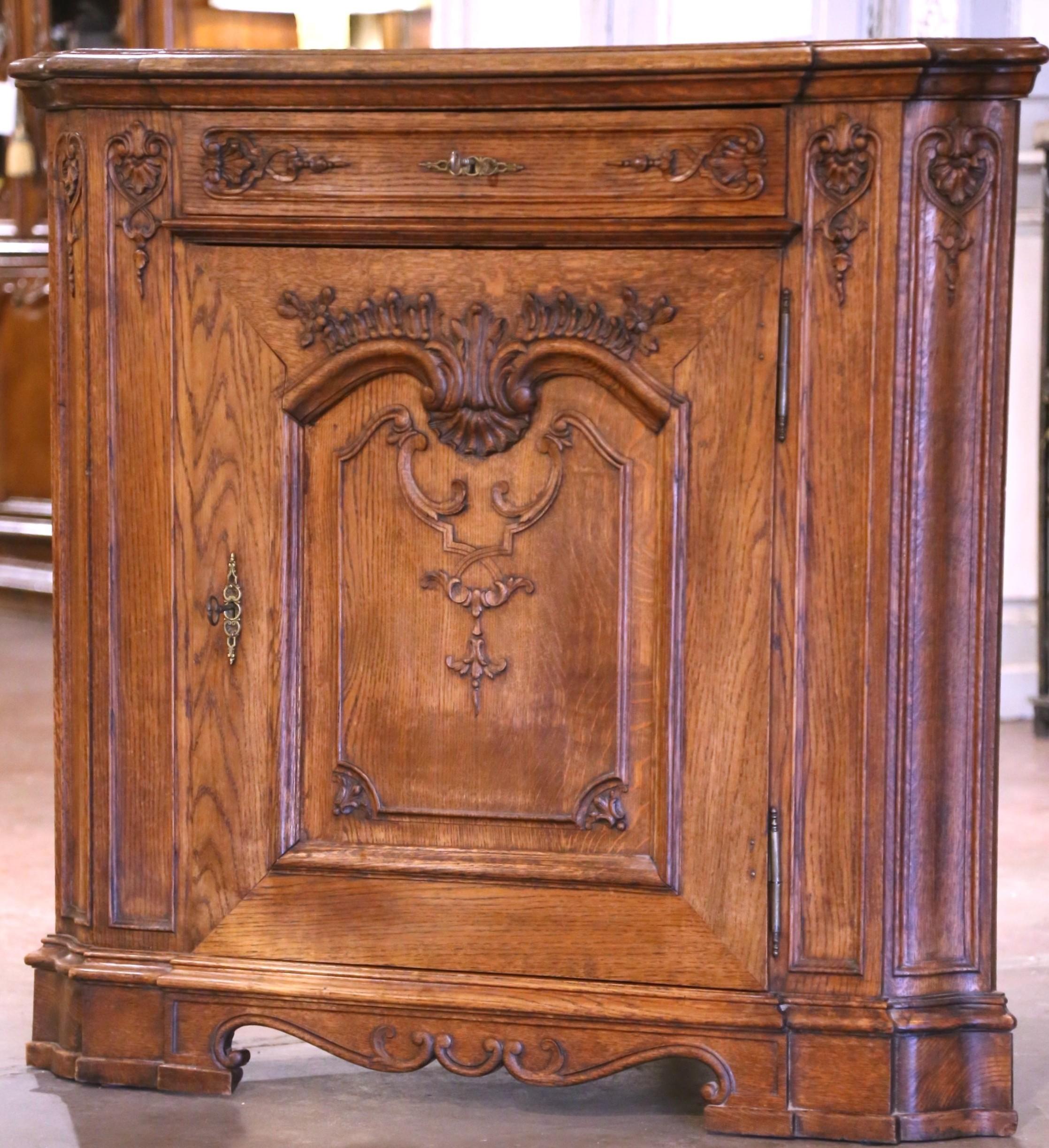 Bringen Sie Eleganz und Stauraum in jede Ecke mit diesem schönen antiken Eckschrank. Der breite Schrank wurde um 1920 in Frankreich aus massiver Eiche gefertigt und steht auf Sockelfüßen über einer Schürze mit Wellenschliff. Er hat eine gewinkelte