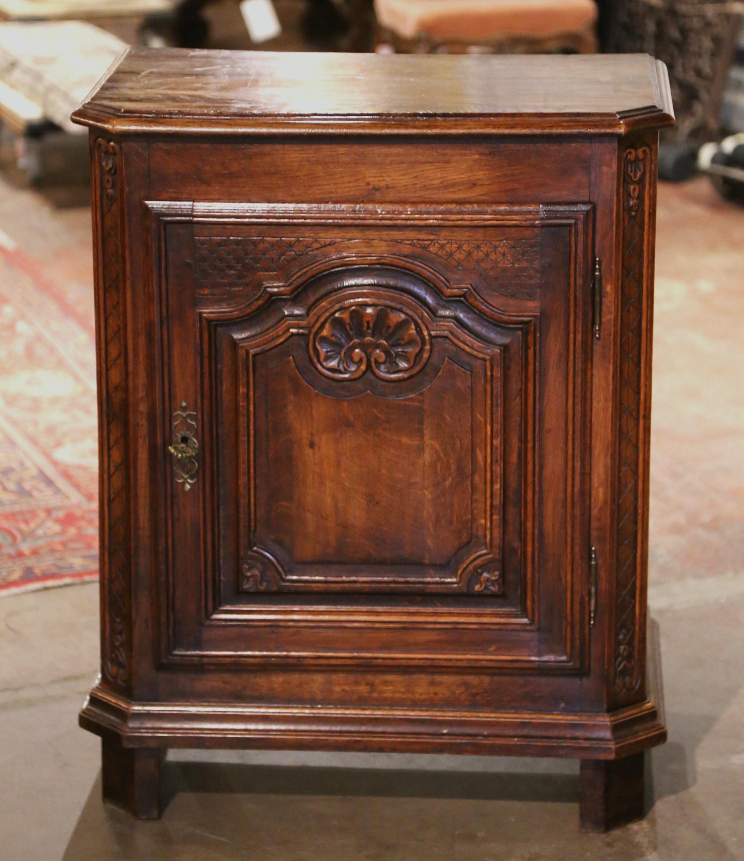 This elegant antique oak “Confiturier” (French for jelly cabinet) was crafted in Normandy, circa 1920. The provincial cabinet stands on square feet over a straight bottom plinth; it is fitted with a single door decorated with carved raised and